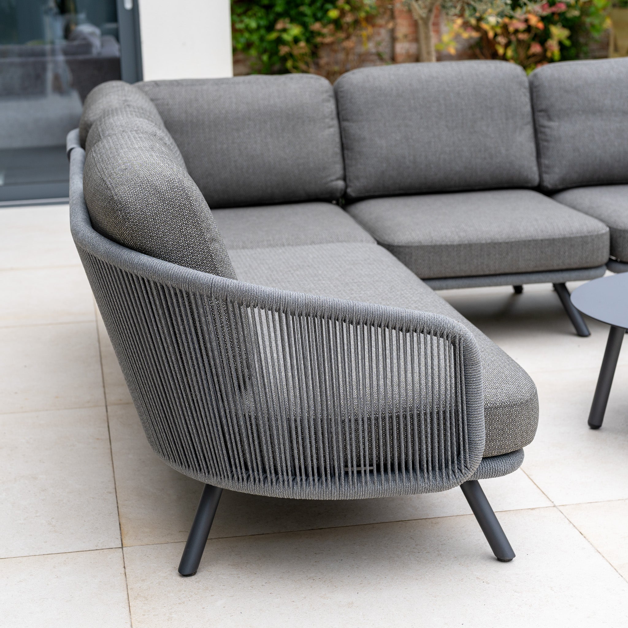 Modern grey outdoor furniture, such as the Dekota Large Corner Sofa Set in Charcoal, features woven rope arms and metal legs for a stylish patio centerpiece.