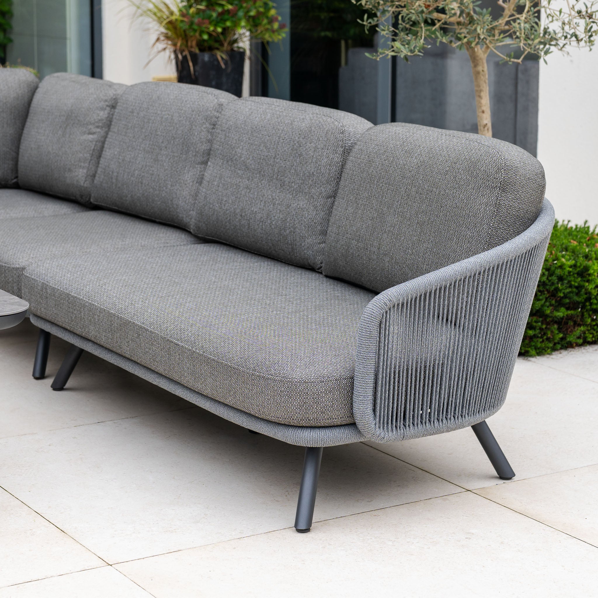 The Dekota Large Corner Sofa Dining Set with Altura Rising Table in Charcoal features cushioned seats and back, perfect for patios. Pair this versatile set with the rising table for stylish and adaptable outdoor entertaining.