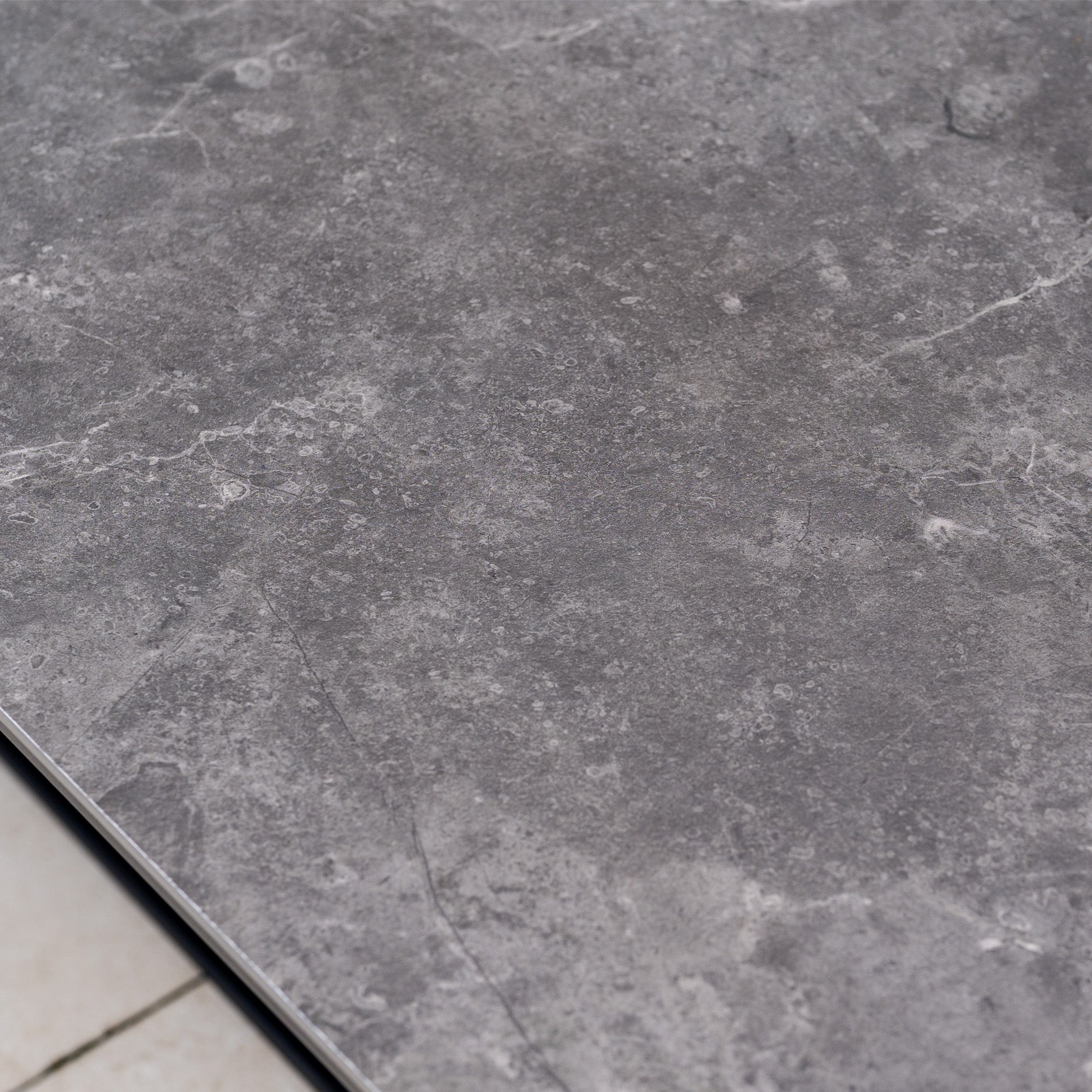 Close-up of a grey stone tile with subtle white veining and a matte, textured surface, perfect for pairing with the Dekota Large Corner Sofa Dining Set with Altura Rising Table in Charcoal for stylish modern spaces.