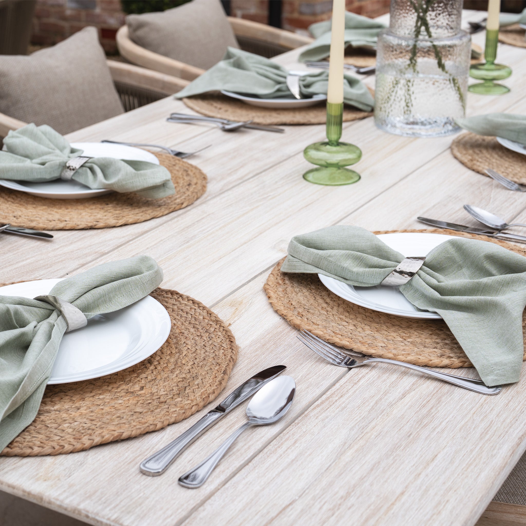 The Evora 8 Seat Rectangular Dining Set in Mocha features a teak table with woven placemats, white plates, sage green napkins, and silverware enhanced by mocha rope detailing for an elegant outdoor retreat.