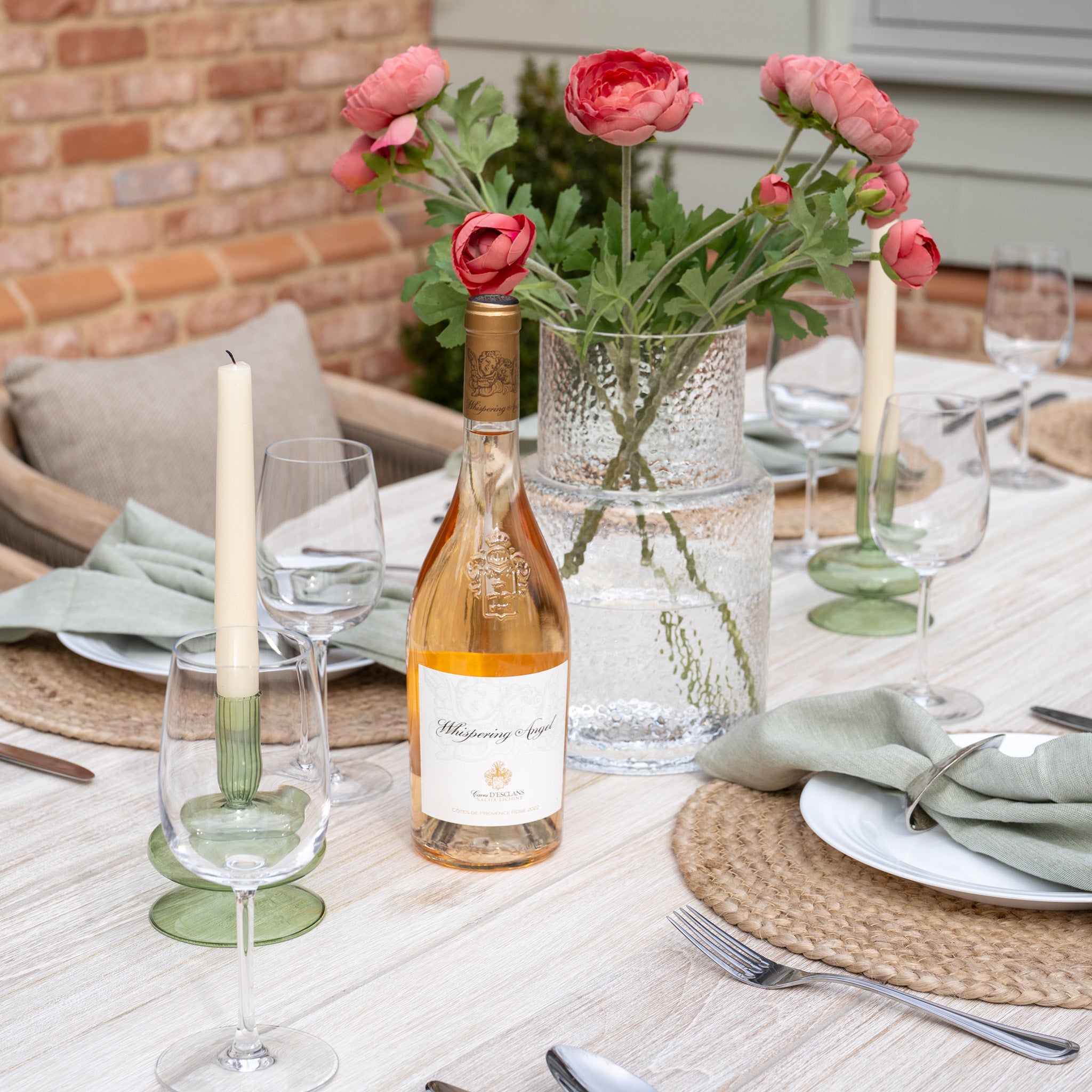 The Evora 8 Seat Rectangular Dining Set in Mocha is elegantly arranged with wine, glowing candlesticks, and pink flowers in a glass vase on its beautiful teak table.