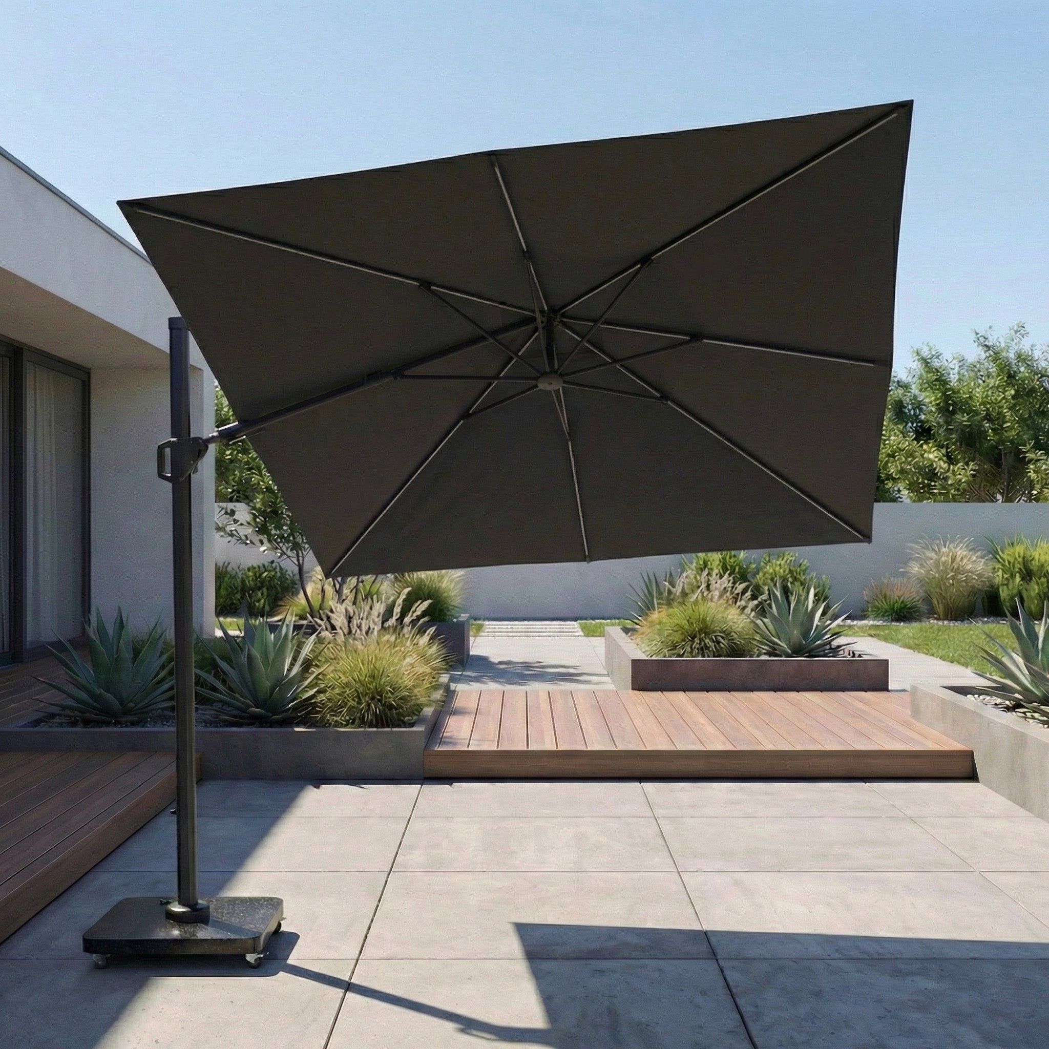 The Glow Challenger T2 3m Square Cantilever Parasol in Anthracite shades a stylish outdoor space with plants, wood decking, and concrete tiles.