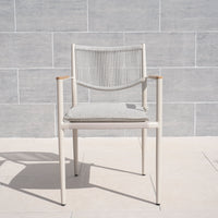 The Tellaro Rope Dining Chair in Latte (6pcs) features a hand-woven rope backrest and cushion, displayed on a light stone floor against a tiled wall.