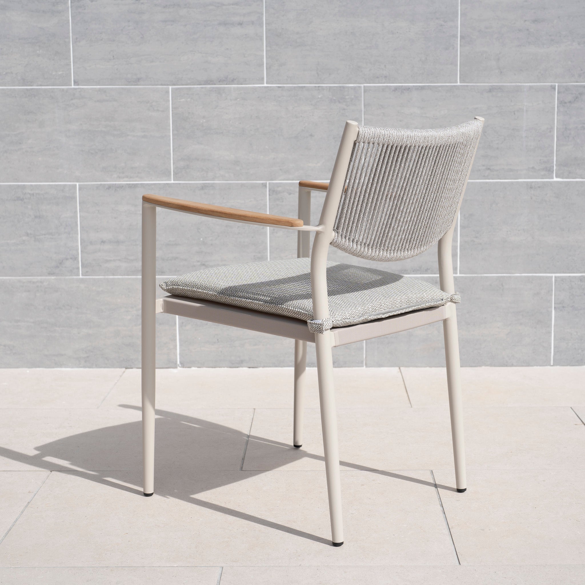 The Tellaro Rope Dining Chair in Latte (6pcs) features a hand-woven rope backrest, metal frame, and wooden armrests, adding elegance to any tiled patio.