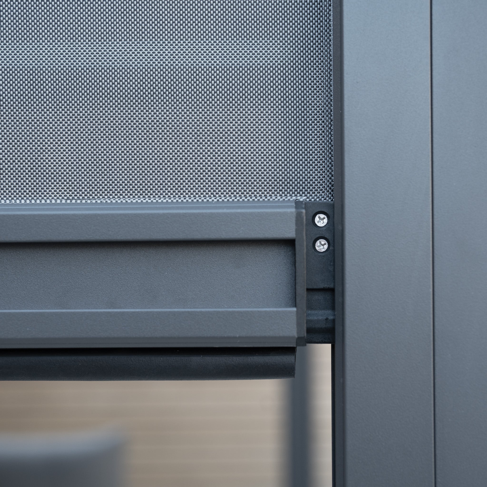 Close-up of a gray metal frame with screws and mesh screen, likely part of a modern structure, featuring sleek design elements reminiscent of the PergoSTET Plus 3m x 4m Rectangular Pergola with 3 Drop Sides and LED Lighting in Grey.