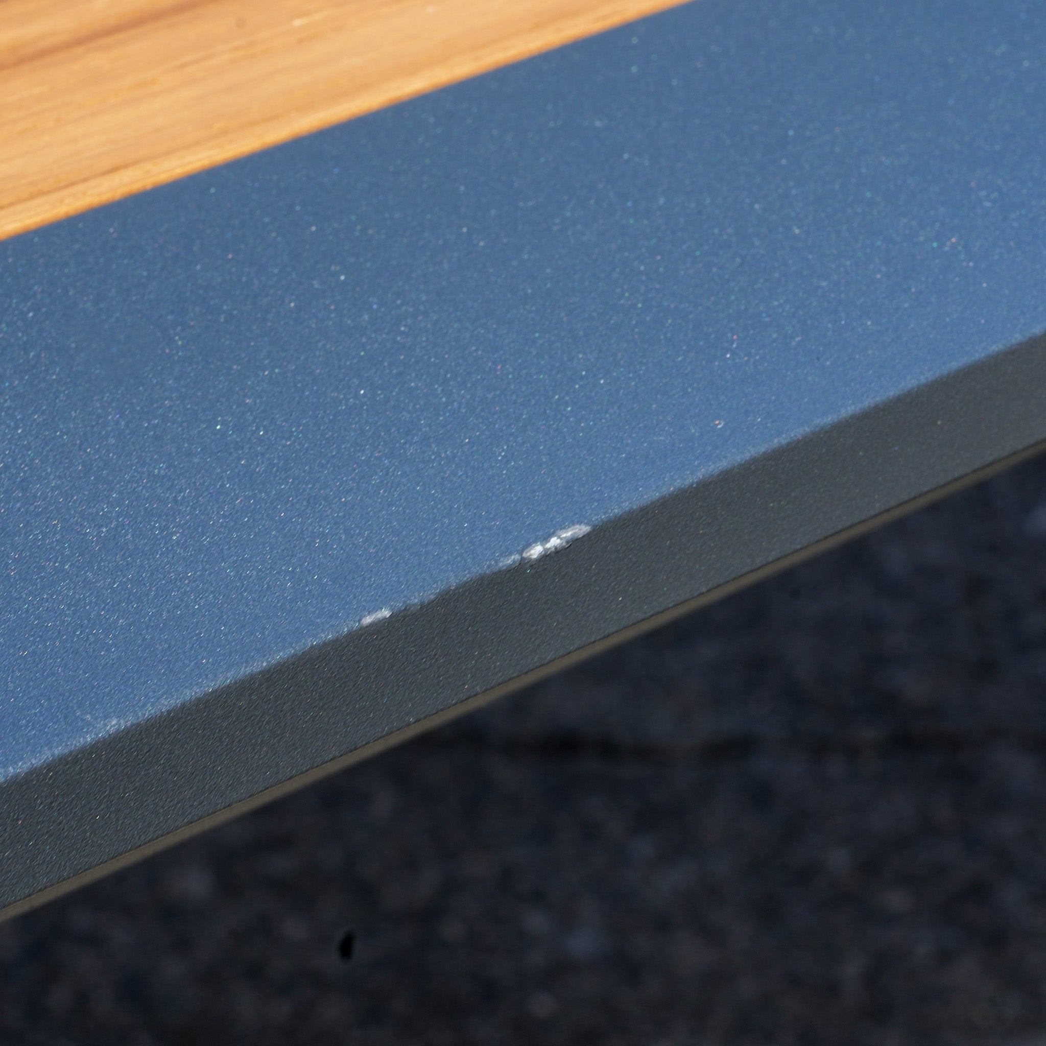 Close-up of a chipped edge on the gray aluminum leg of the Pier Extending Dining Table with Teak Top (Ex Display).