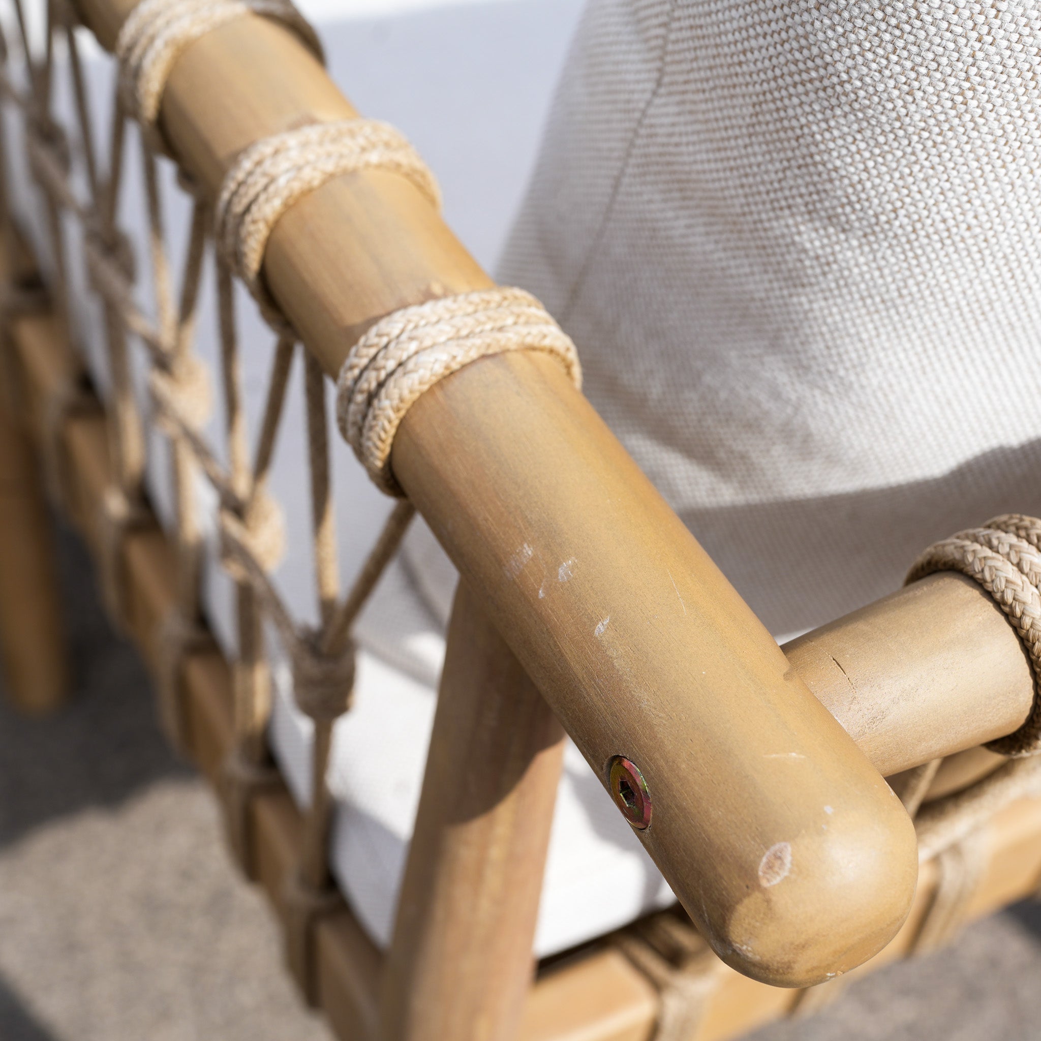 Close-up of a chair from the Paia 8 Seat Round Dining Set (Ex Display), showcasing acacia wood and rope accents, paired with a light, water-resistant cushion.