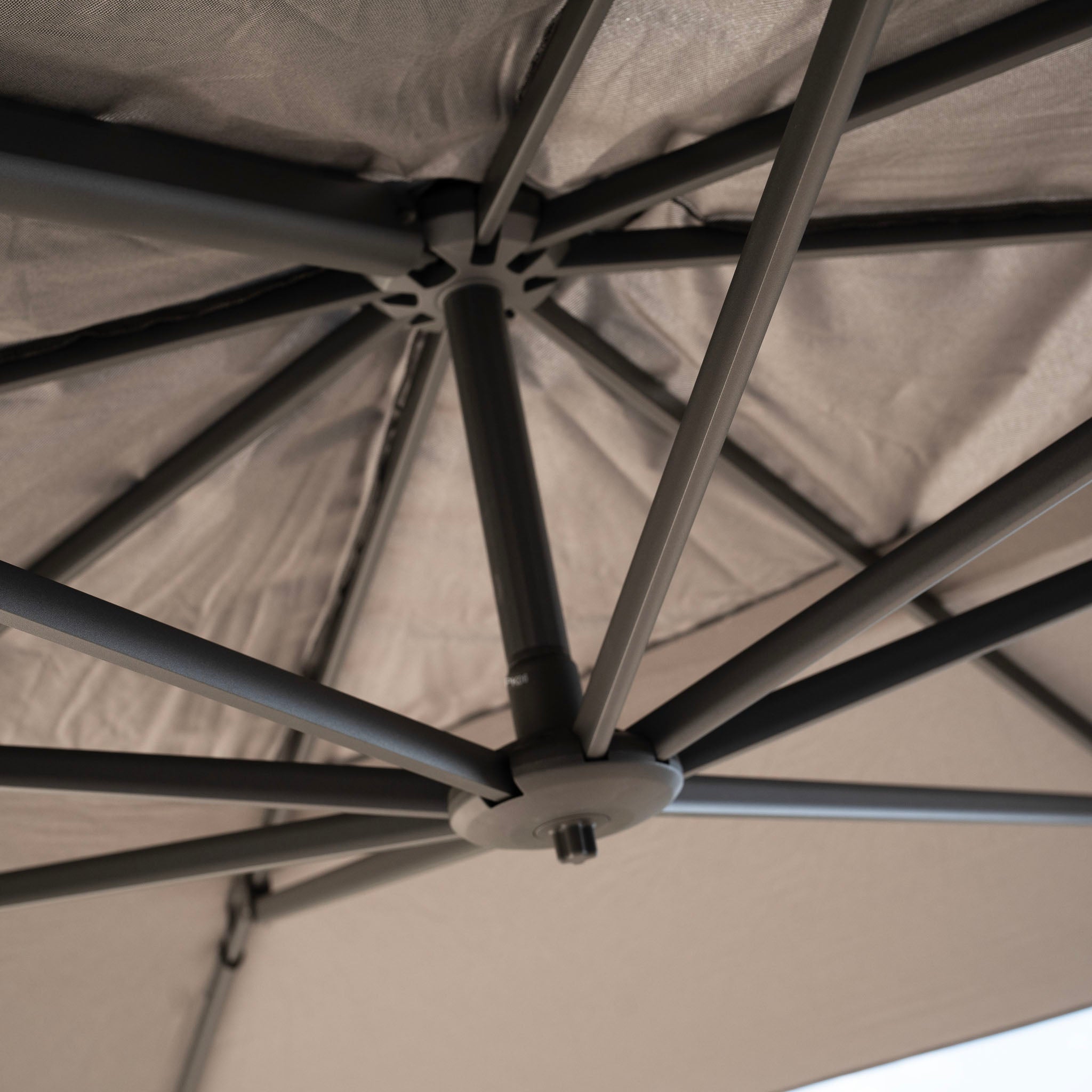 Close-up view of the underside of the Hacienda 3m x 4m Cantilever Parasol in Charcoal showcasing its sturdy metal frame and UV-resistant beige fabric, designed for 360-degree rotation.