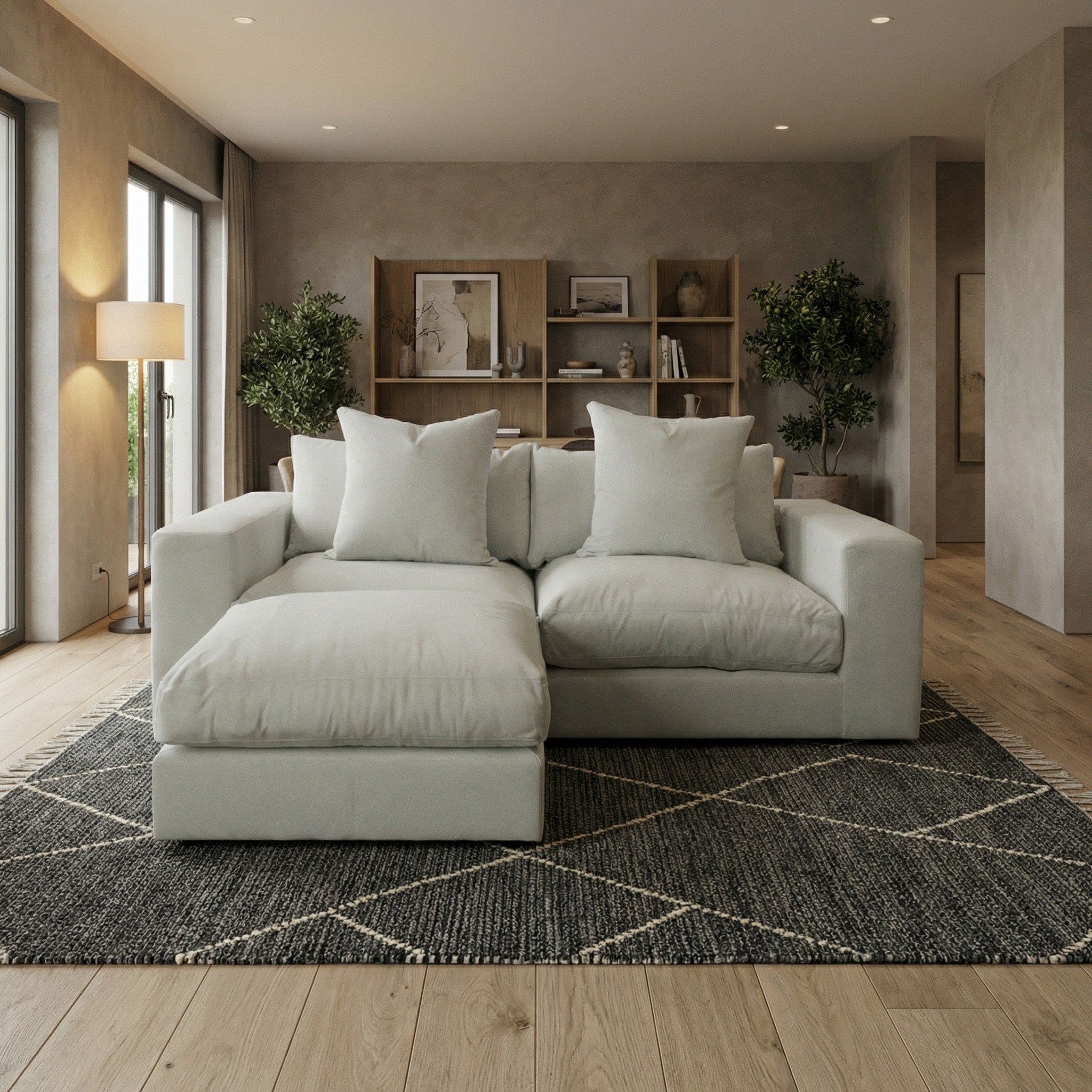 Modern living room with the Hampshire Modular 2 Seat Sofa in Classic Grey featuring duck feather cushions, a rug, floor lamp, and bookshelves with decor and plants.