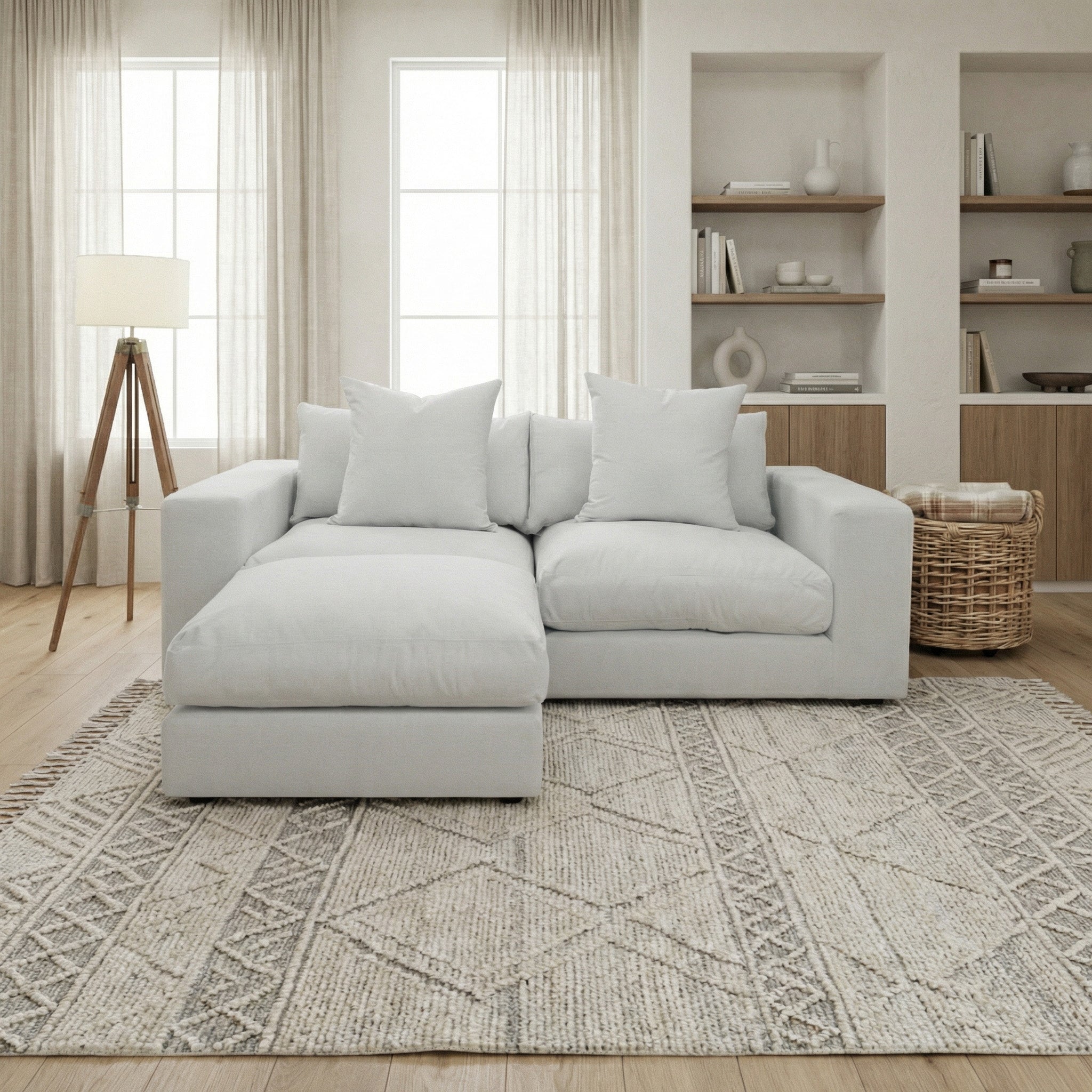 A modern living room with a Hampshire Modular 2 Seat Sofa in Dove Grey featuring duck feather cushions, a patterned rug, and built-in shelves.