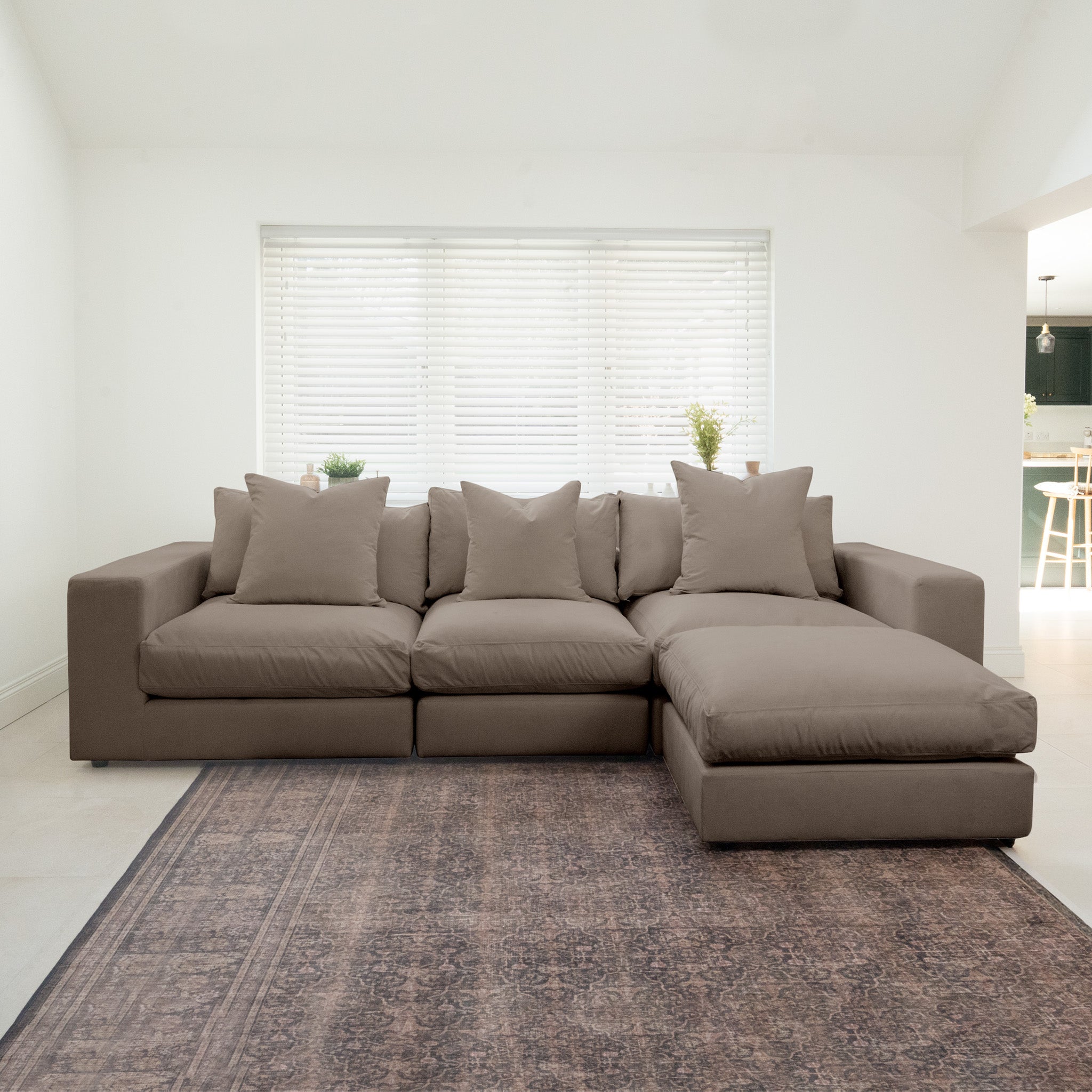 The Hampshire Modular 3 Seat Sofa in Cocoa, featuring duck feather cushions, sits on a patterned rug in a bright, minimalist living room.