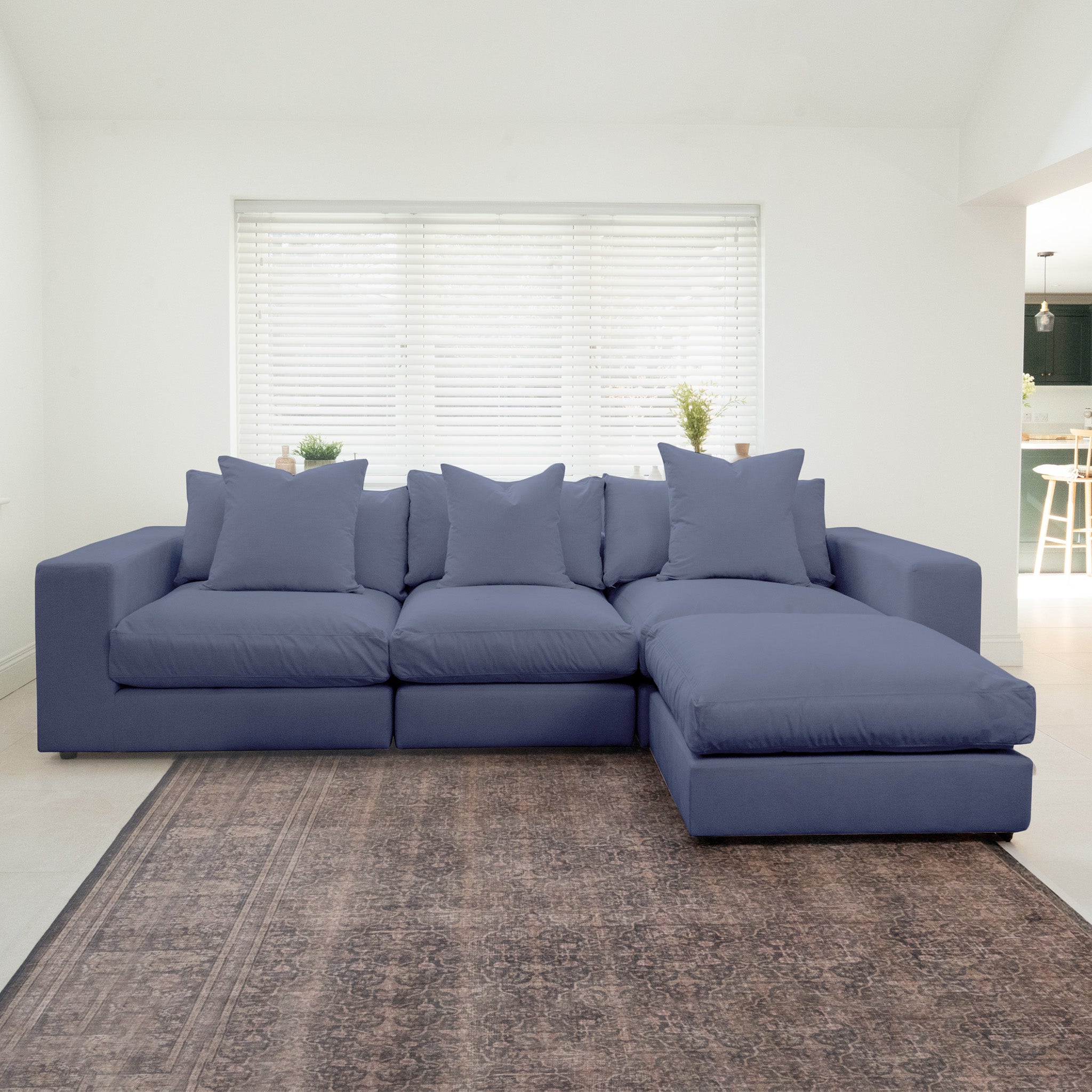 Hampshire Modular 3 Seat Sofa in Midnight Blue with duck feather cushions on a patterned rug in a bright living room featuring white blinds and plants.