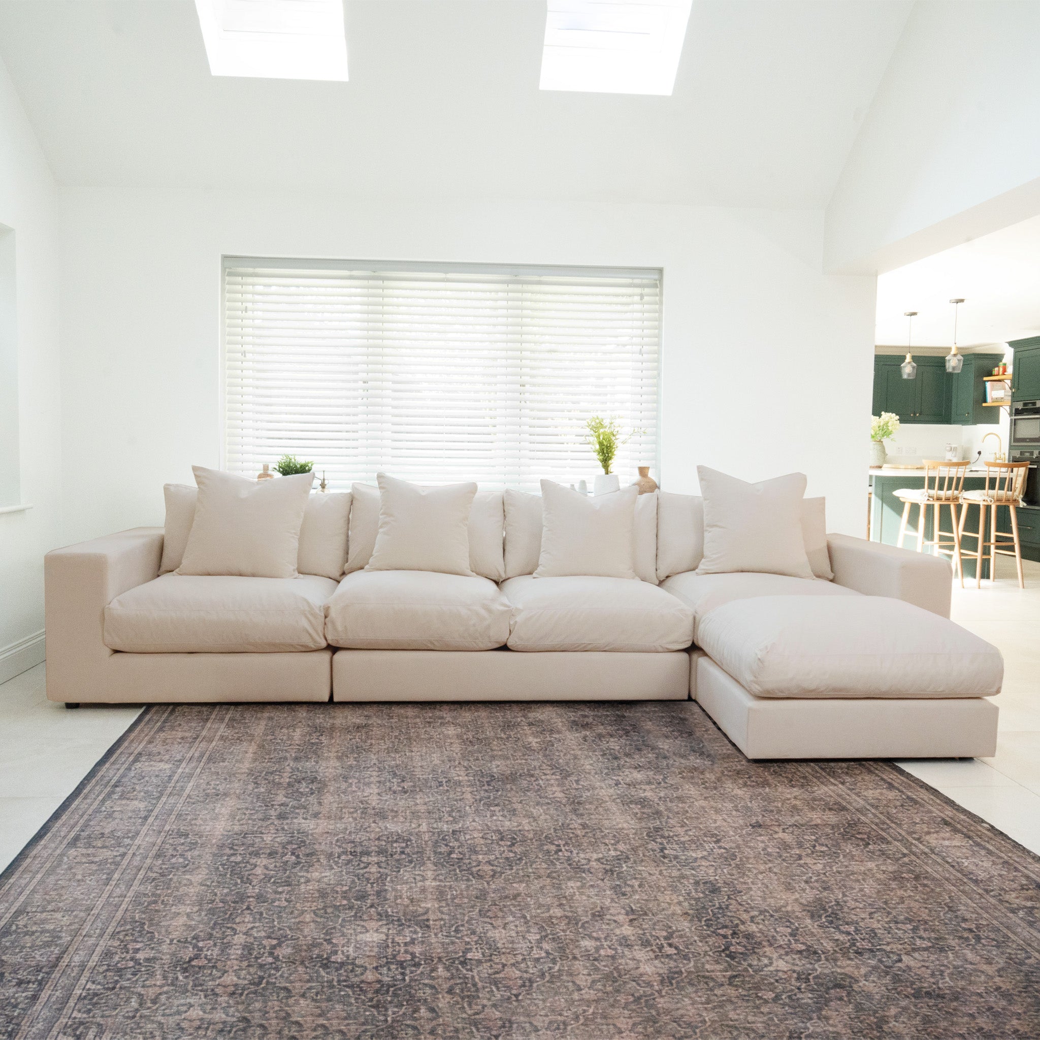 The Hampshire Modular 4 Seat Sofa in Beige with duck feather cushions sits on a patterned rug in a bright, modern living room.