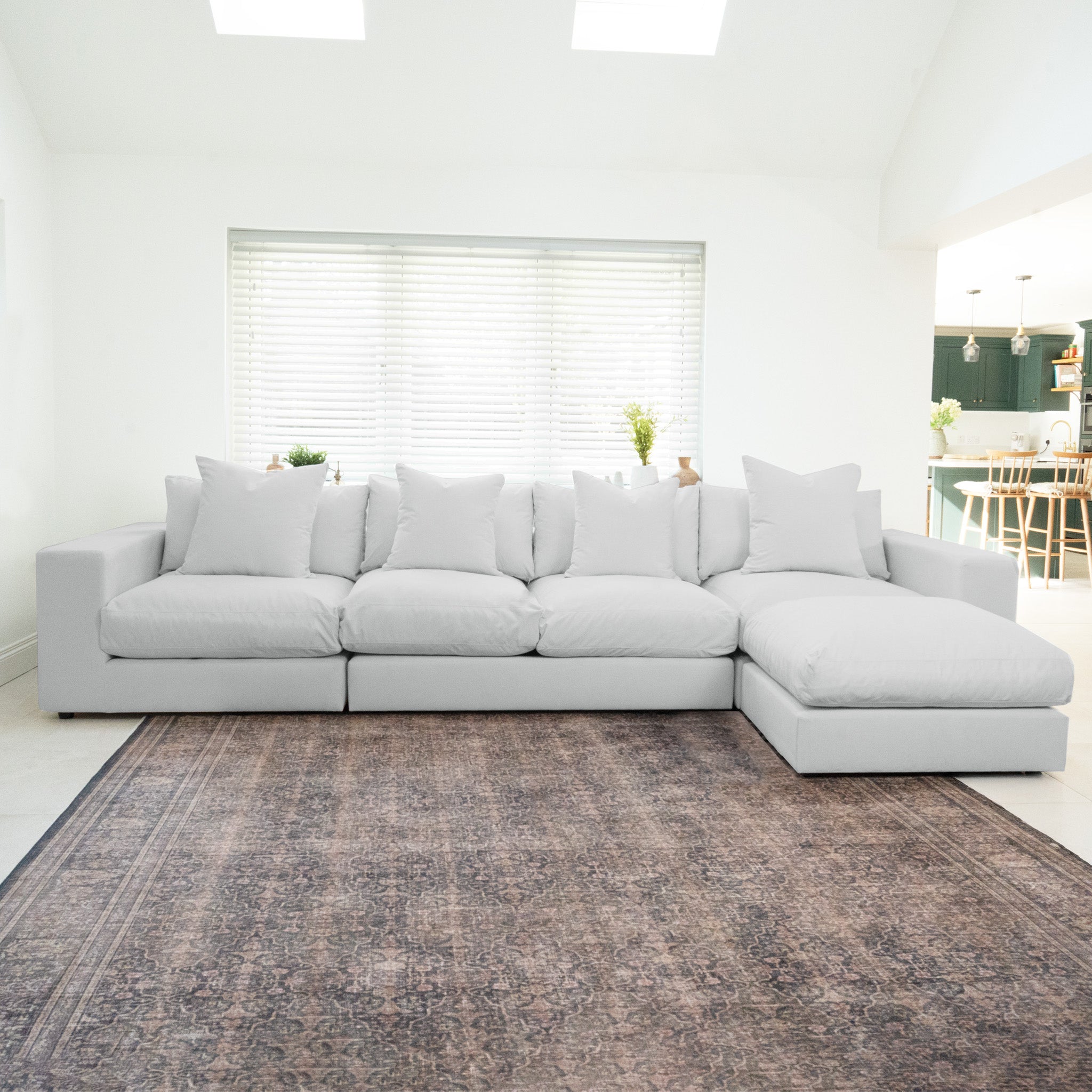 The Hampshire Modular 4 Seat Sofa in Dove Grey with duck feather and down cushions sits on a patterned rug in a bright, modern living room.