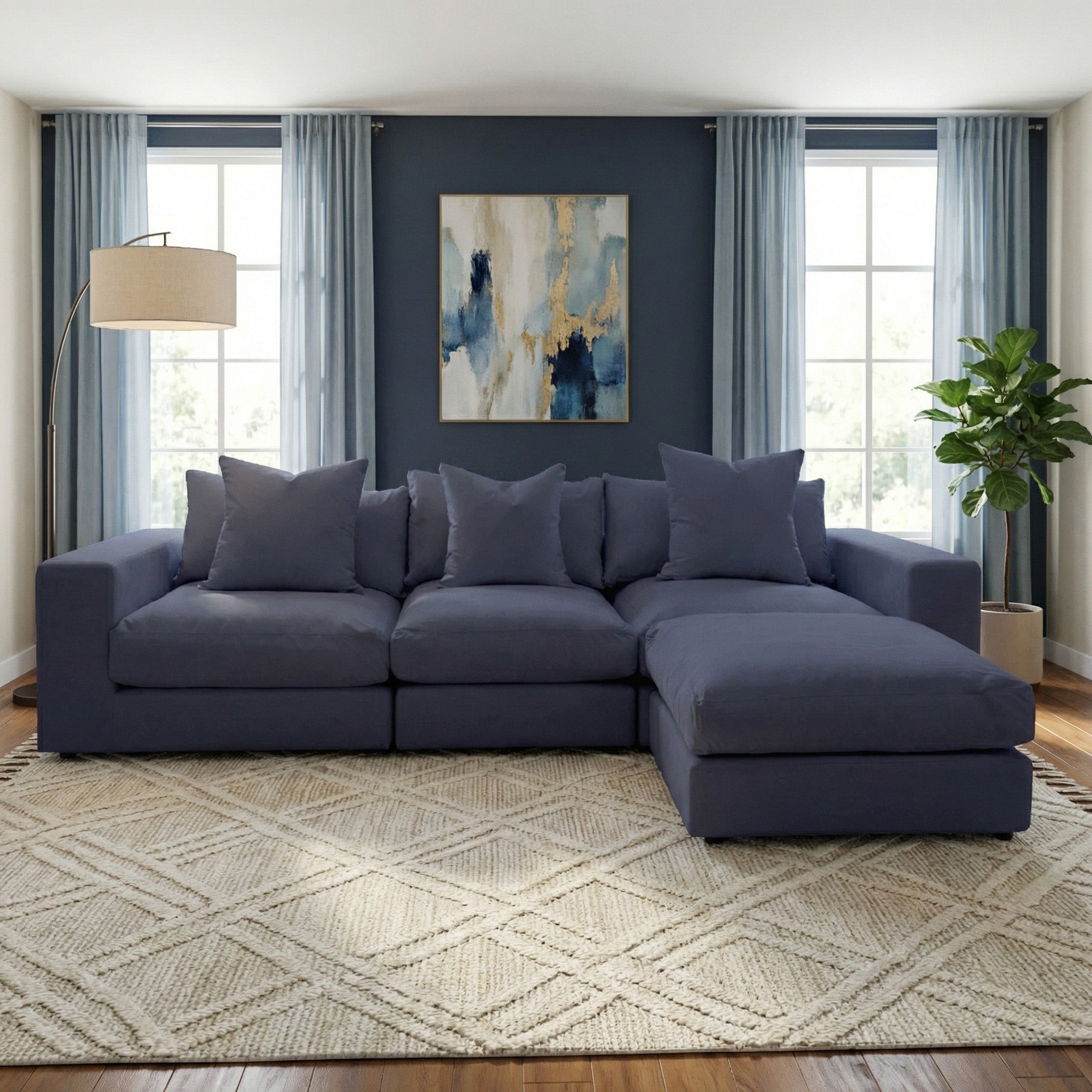 Modern living room with a Hampshire Modular 3 Seat Sofa in Midnight Blue, abstract wall art, large windows, and a patterned rug—elegant comfort handmade in England.