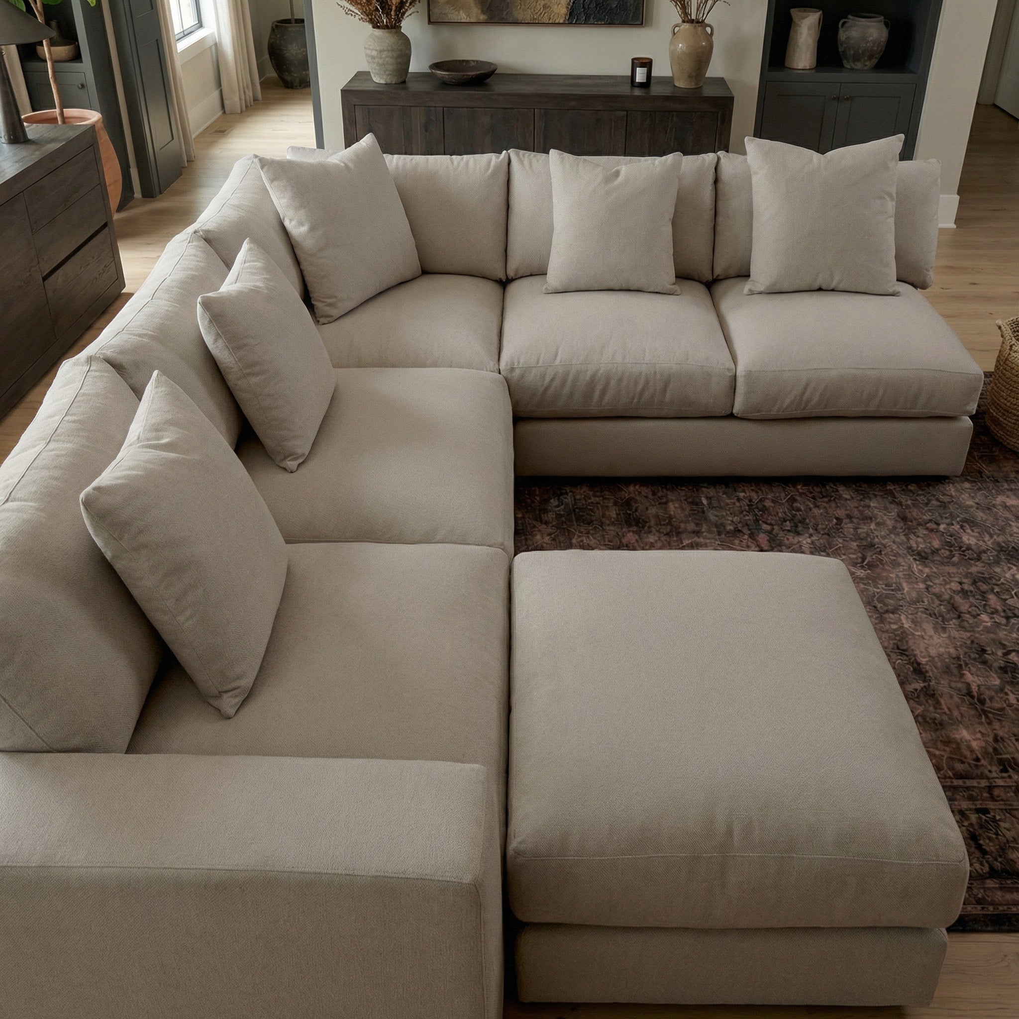 The Hampshire Modular Corner Sofa in Cocoa, with matching pillows and ottoman, creates a cozy, modern living room. This flexible modular sofa offers timeless style and adaptable seating for any space.