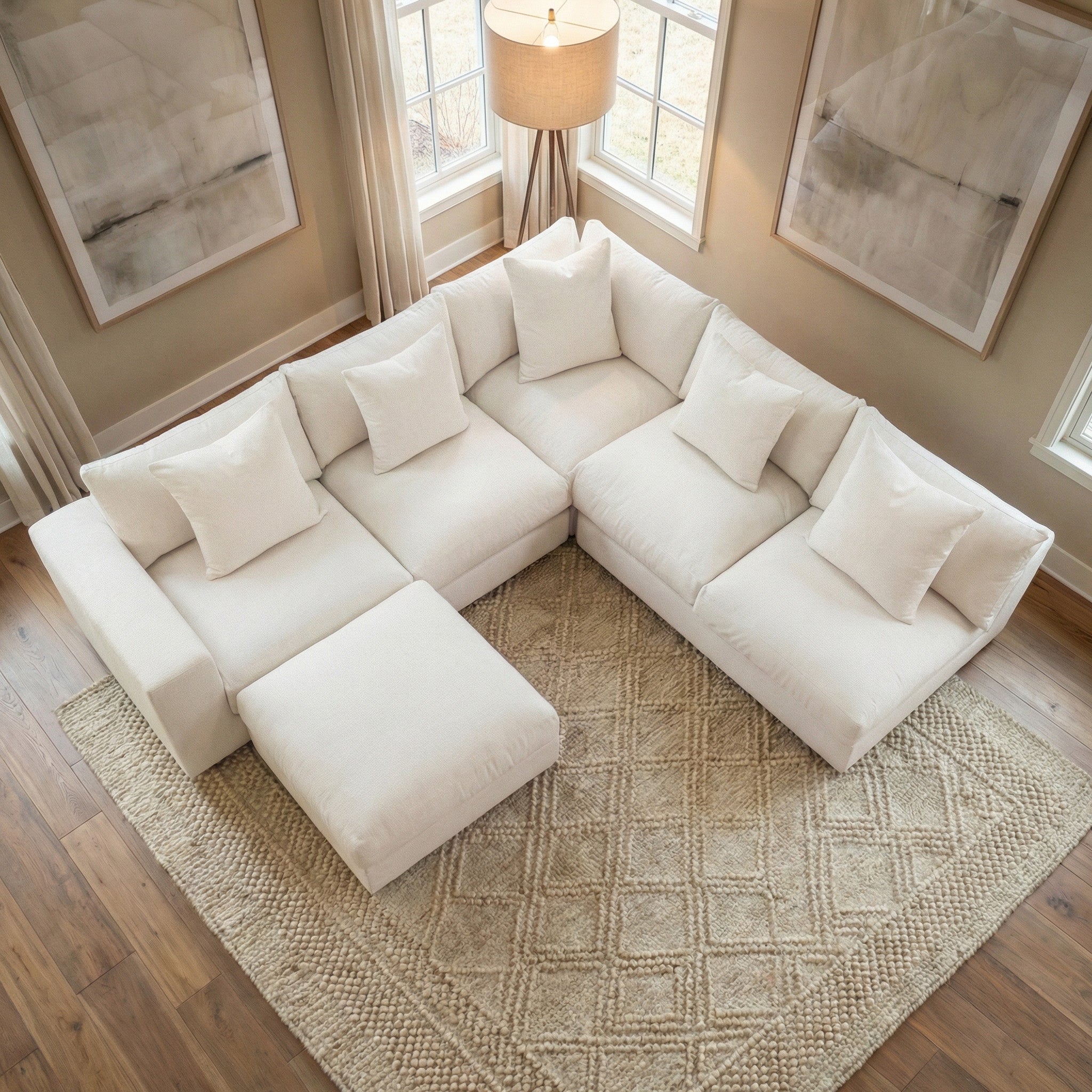 The Hampshire Modular Corner Sofa in Ivory with matching pillows sits on a textured rug in a bright, modern living room.