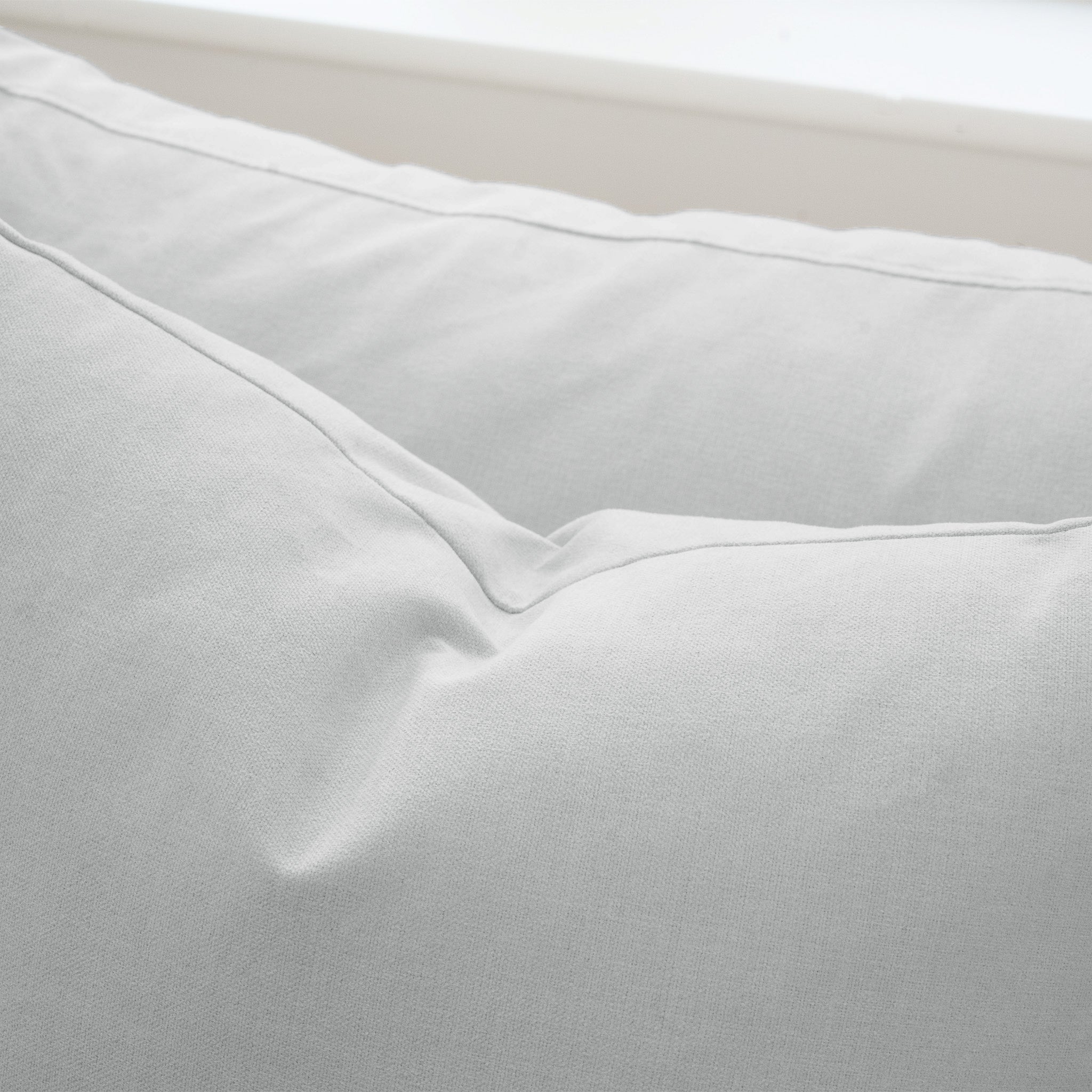 Close-up of a light gray pillow with soft, smooth fabric and visible seams, designed to complement the Hampshire Modular 3 Seat Sofa in Dove Grey, which features plush duck feather cushions.