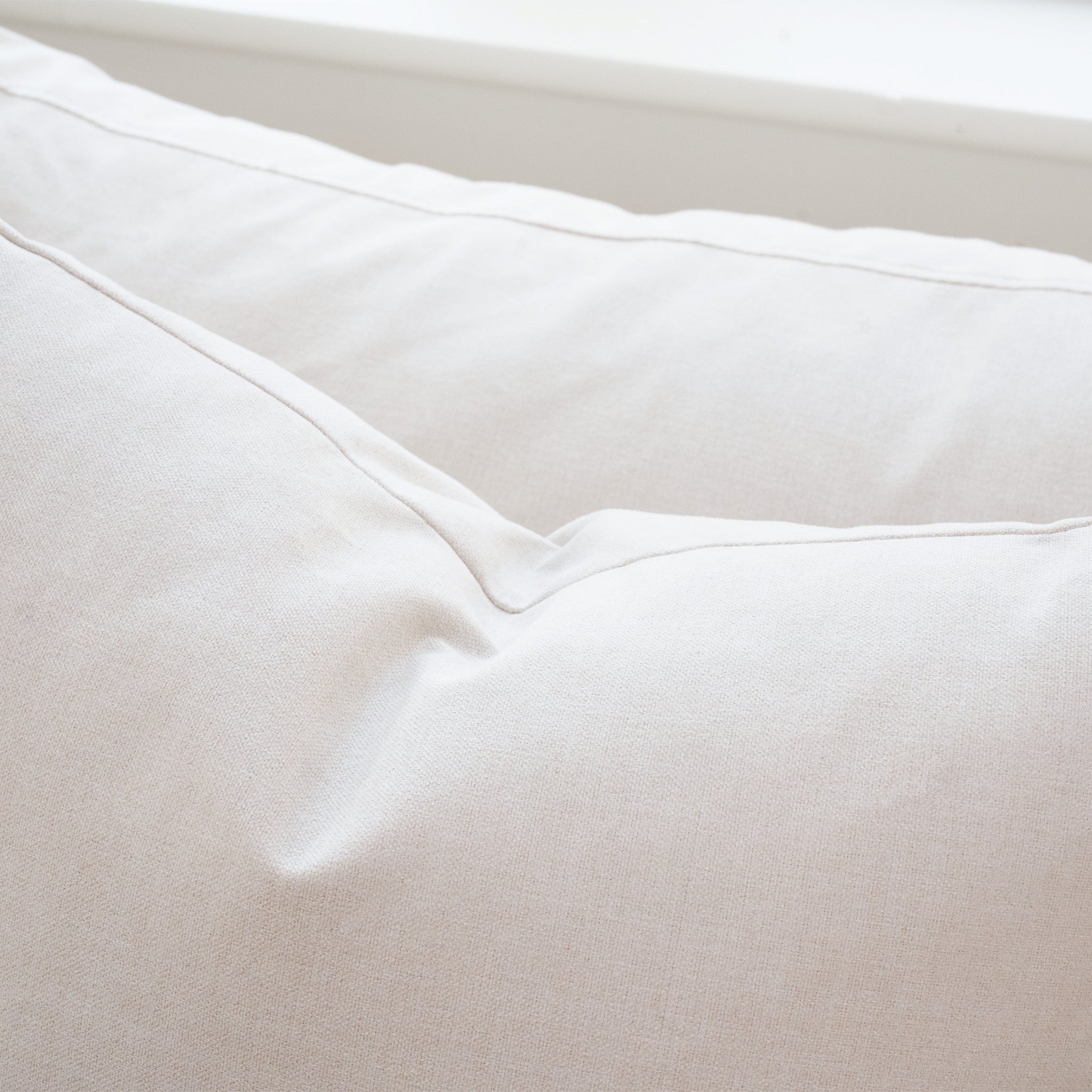 Close-up of a white pillow with stitching, set against a white background—perfect for pairing with the Hampshire Modular Corner Sofa in Ivory and its luxurious duck feather and down cushions.