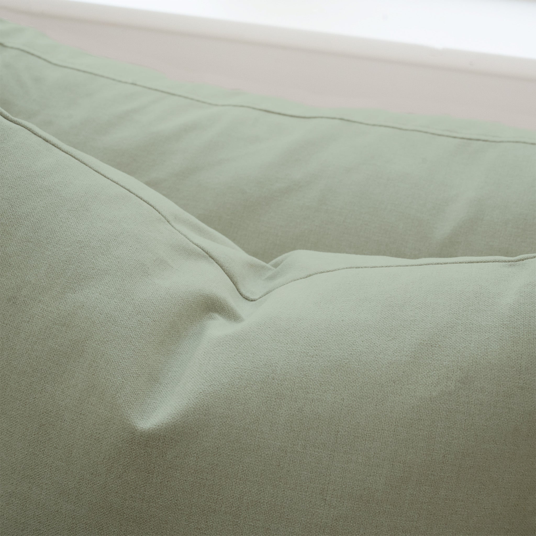 Close-up of a light green pillow with visible stitching and soft, textured fabric, designed to complement the Hampshire Modular 2 Seat Sofa in Moss Green and filled with plush duck feather cushions.