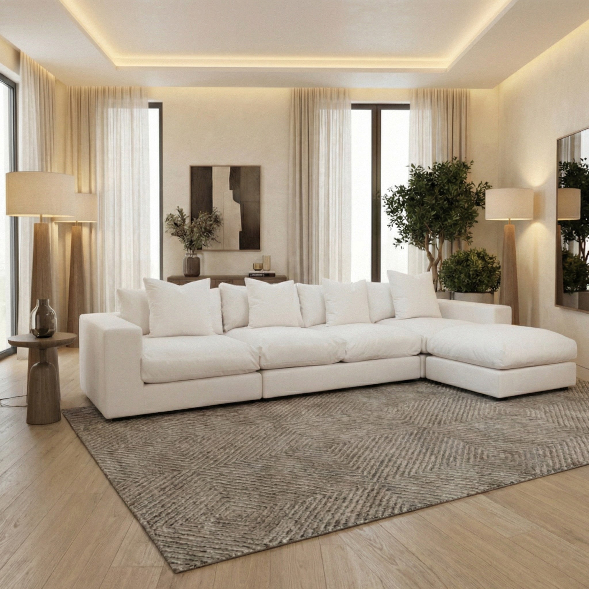 A modern living room with the Hampshire Modular 4 Seat Sofa in Ivory featuring duck feather cushions, neutral decor, large windows, a cozy rug, stylish lamps, and lush indoor plants.