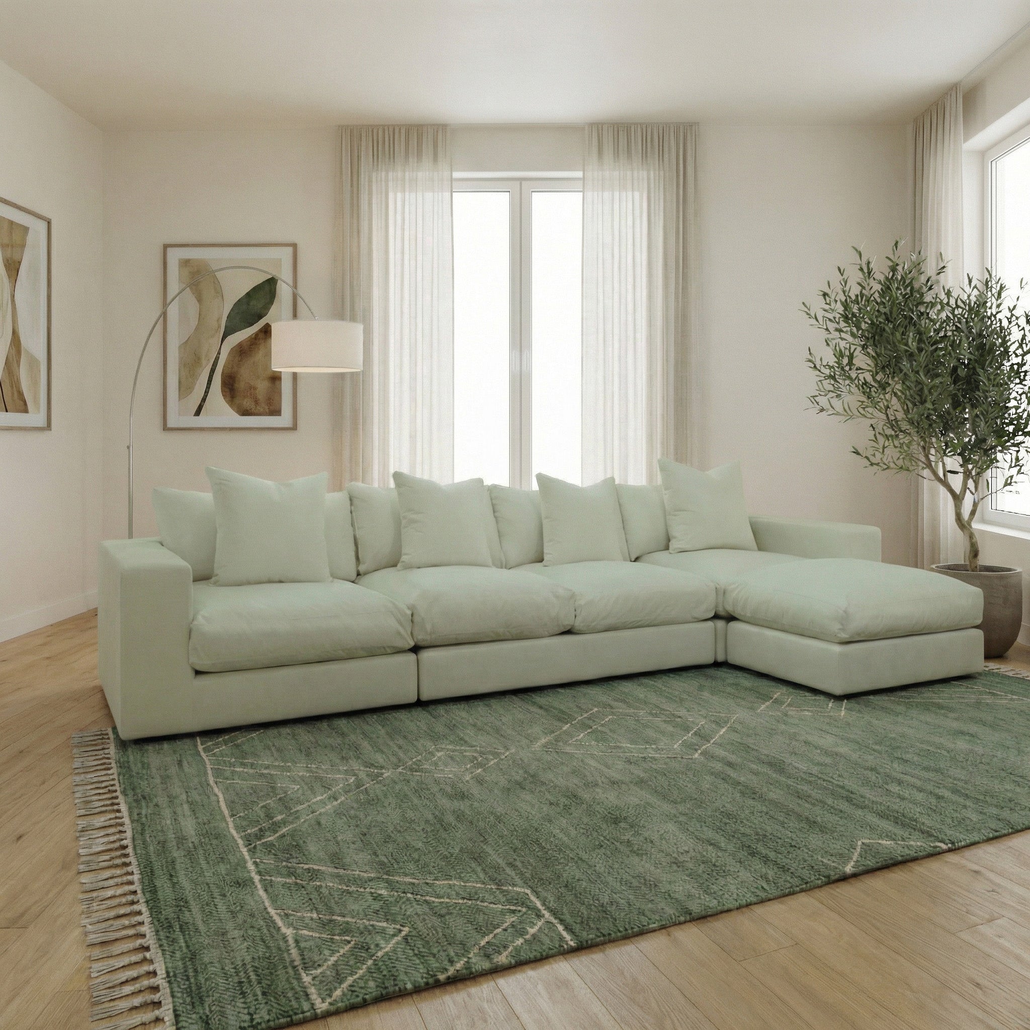 Light-filled living room with a Hampshire Modular 4 Seat Sofa in Moss Green featuring duck feather cushions, plus a green rug, floor lamp, art, and a potted plant.