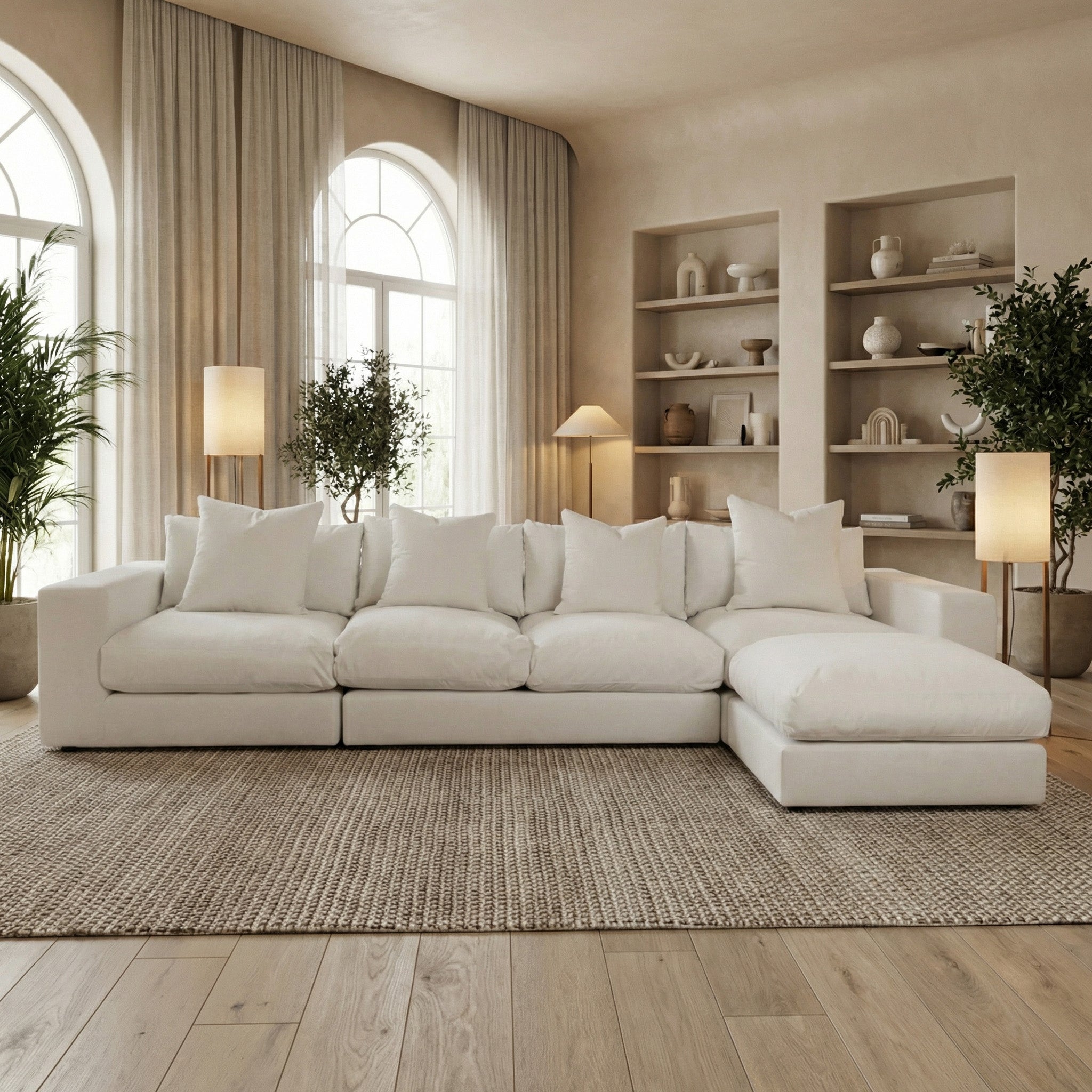 A modern living room with a Hampshire Modular 4 Seat Sofa in warm grey, soft duck feather cushions, neutral decor, and natural light from arched windows.