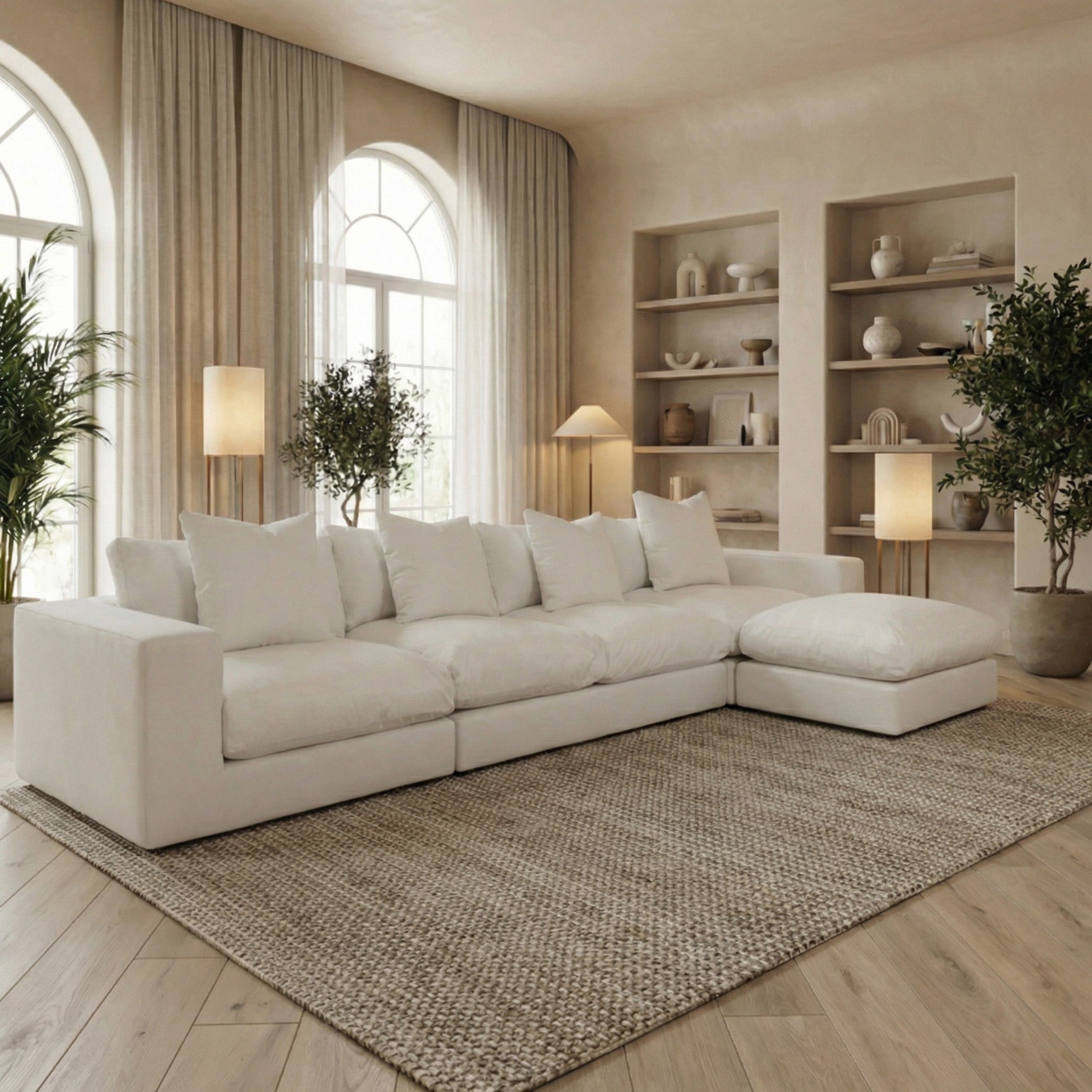 Modern living room featuring the Hampshire Modular 4 Seat Sofa in Warm Grey with duck feather cushions, complemented by indoor plants, shelves, and gentle natural lighting.