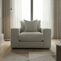 A Hampshire Modular Armchair in Classic Grey with feather and down cushions sits by a window with sheer curtains in a modern room.