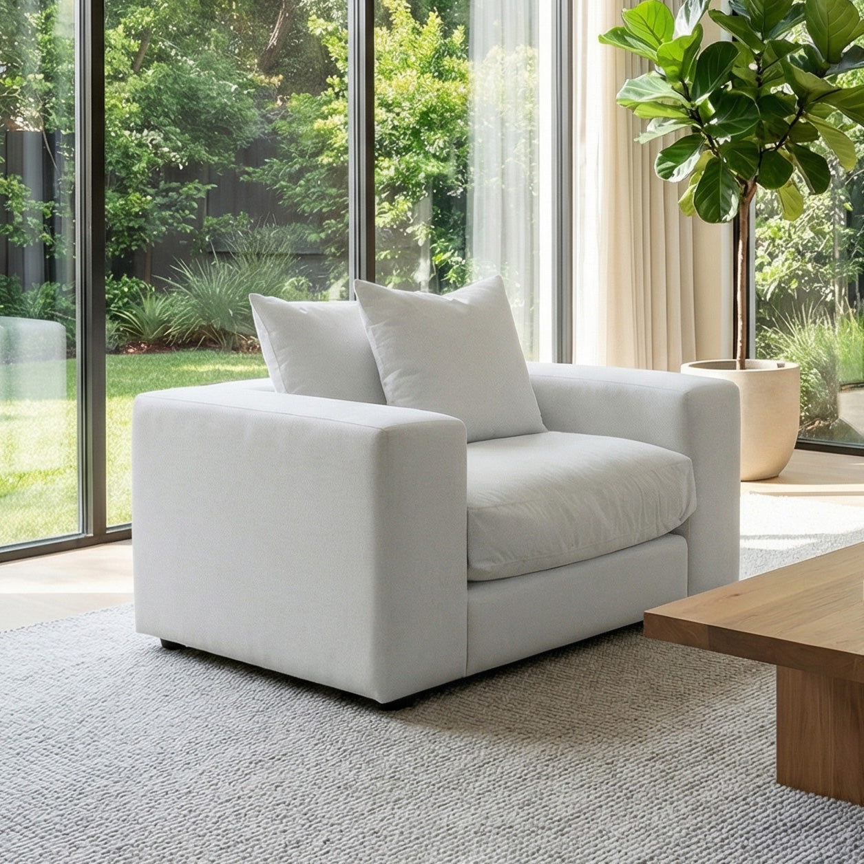 The Hampshire Modular Armchair in Dove Grey, handmade in England with duck feather cushions, sits by large windows overlooking a green garden.