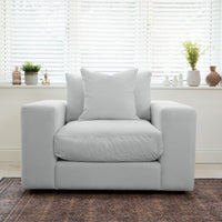 A spacious Hampshire Modular Armchair in Dove Grey with plush cushions sits in front of a window with white blinds and potted plants.