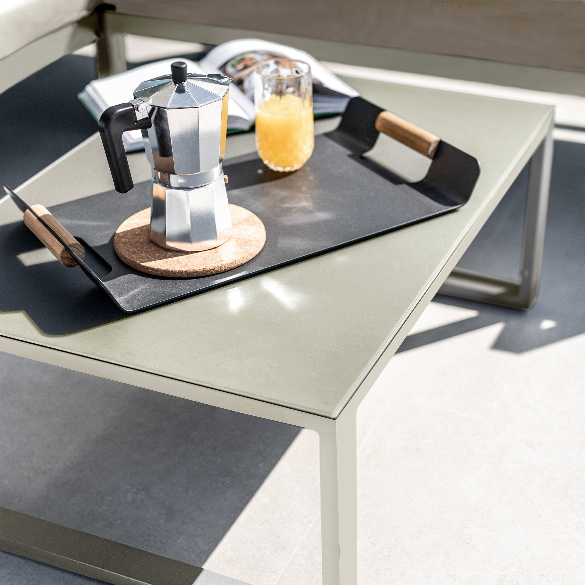 A metal tray with a moka pot, orange juice, and a knife sits on the coffee table of the stylish Havana Corner Group Set with Reclining Feature in Latte.