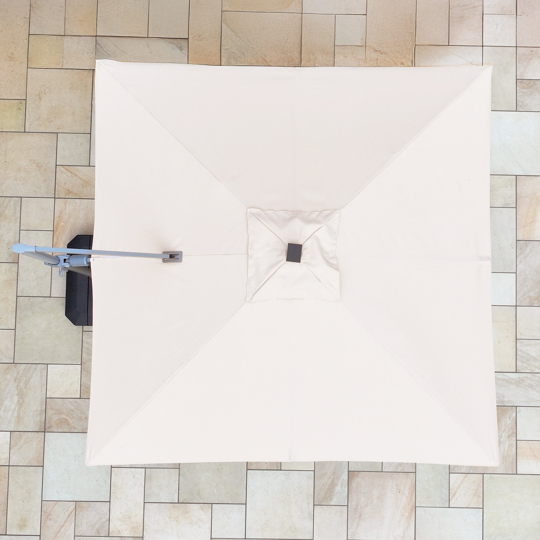 From above, the Hera 2.7m Square Cantilever Parasol in Beige shows off its elegance, offering UV50+ protection and featuring subtle LED lighting that adds an ambient glow to the tiled floor below.