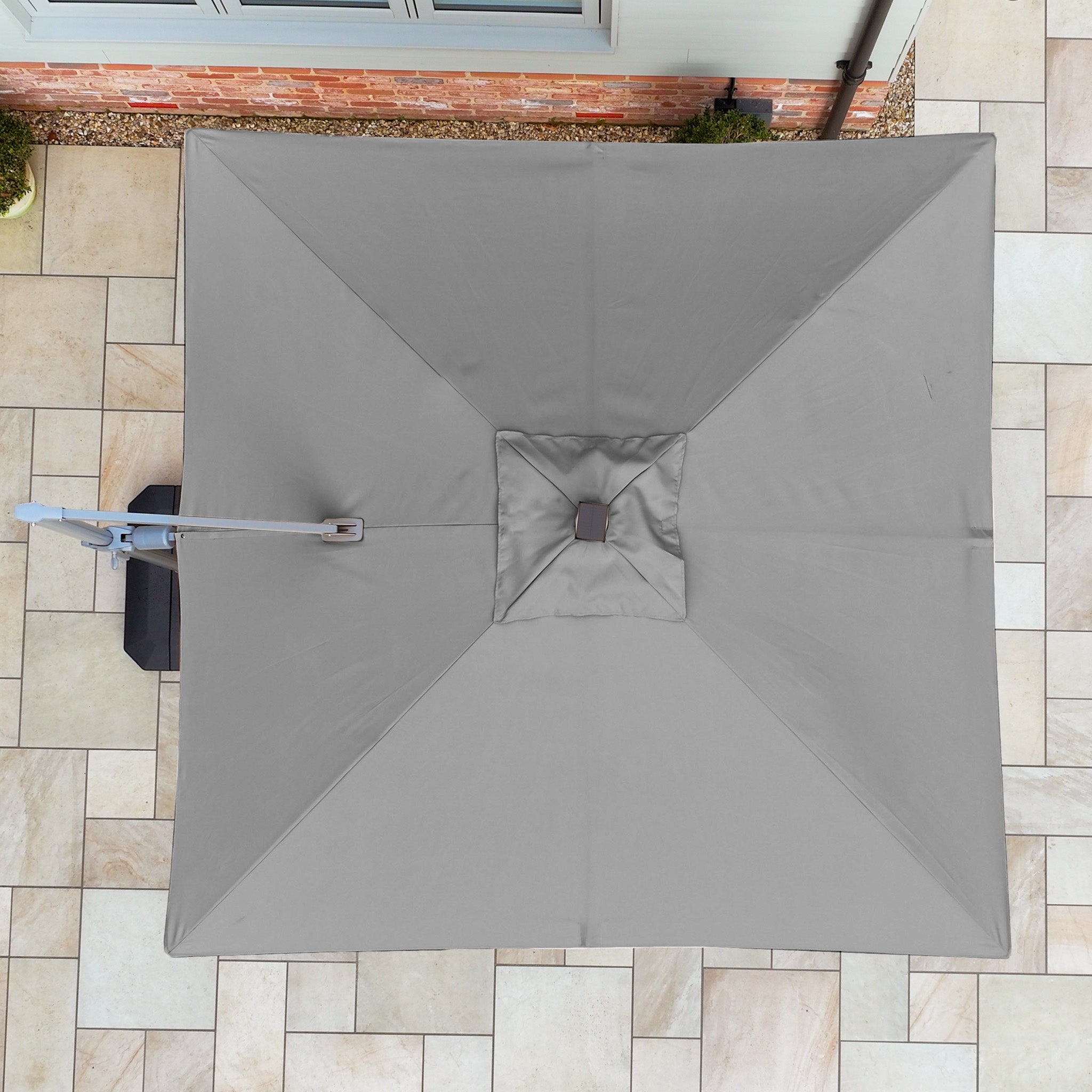 A top view of the Hera 2.7m Square Cantilever Parasol with LED Lighting in Charcoal, featuring UV50+ fabric, shading a tiled outdoor area.