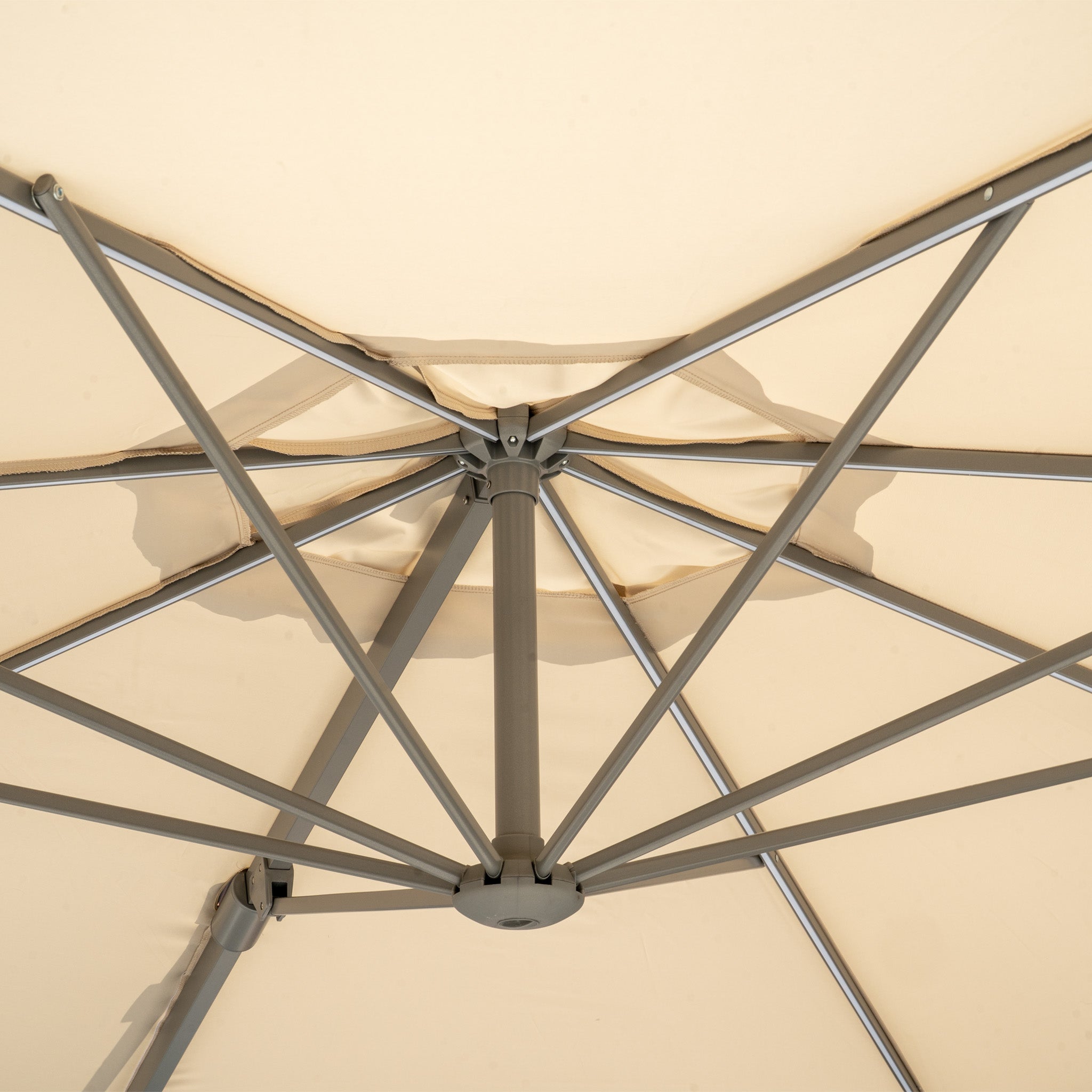 Underside view of the Hera 3m Round Cantilever Parasol with LED Lighting in Beige, featuring metal spokes radiating from the center.