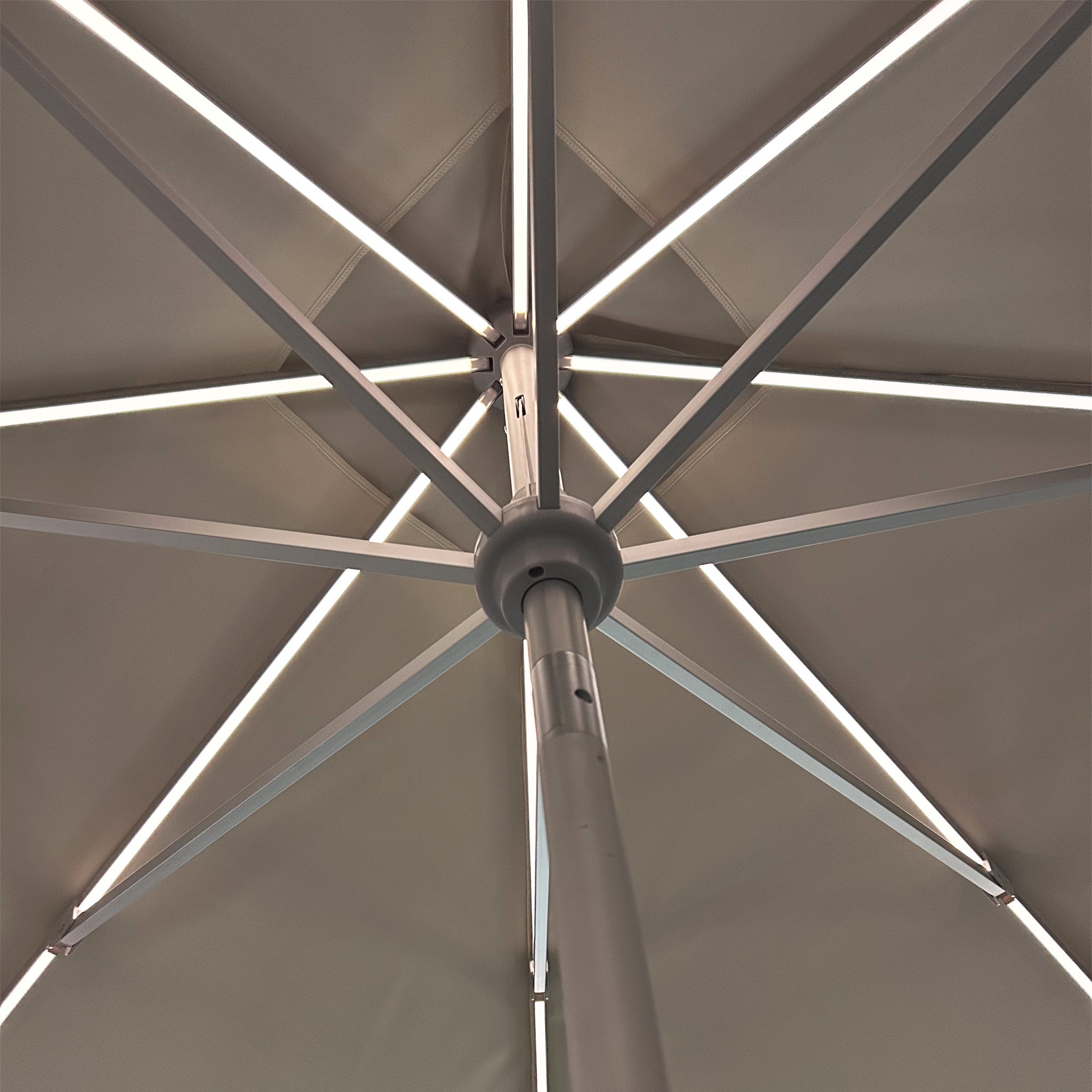 The Zelos 3m x 2m Rectangular Parasol with LED Lighting in Cream dazzles from beneath with its radial metal spokes and central pole forming a geometric pattern, while offering excellent UV protection.