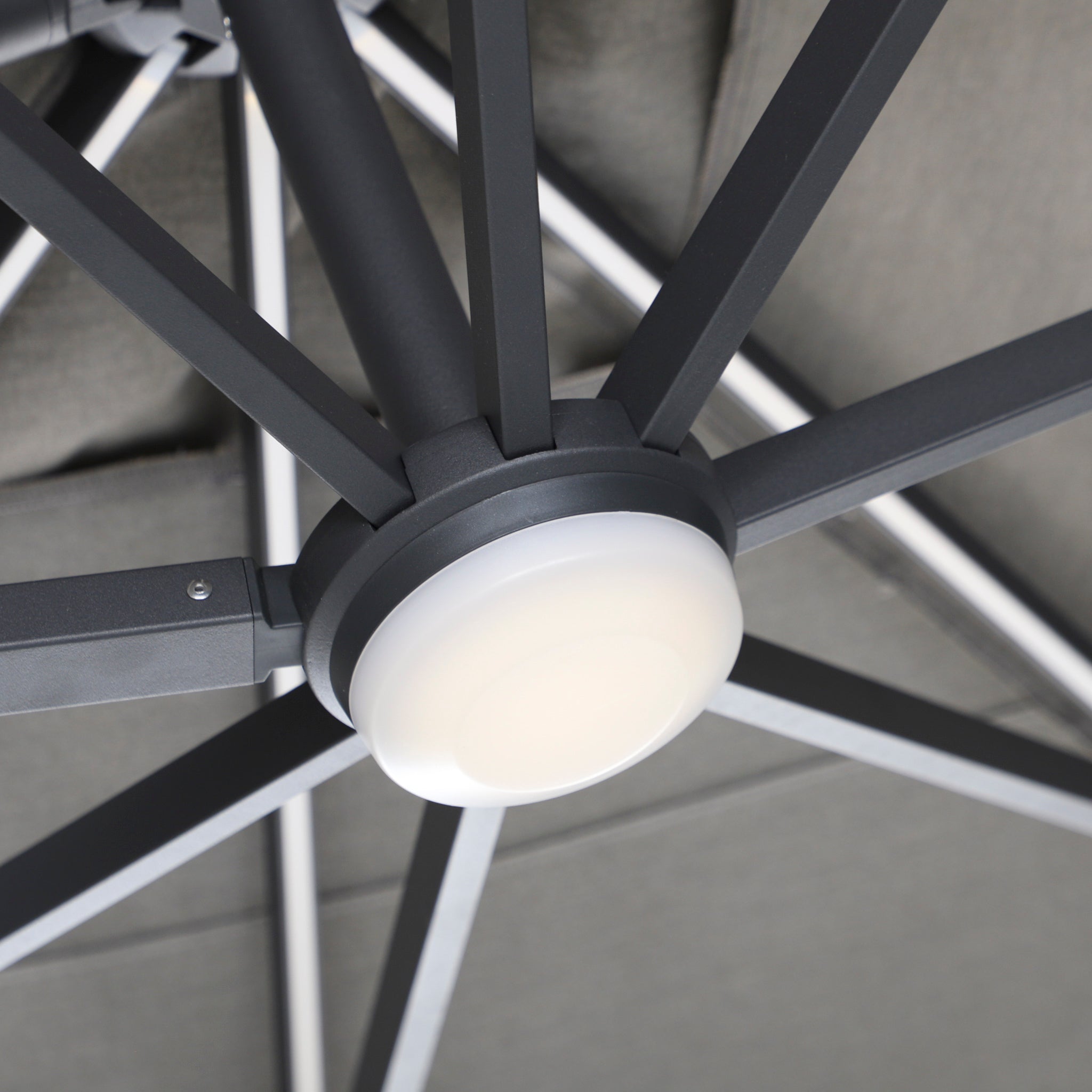Close-up of the Volos 3m x 3m Square Cantilever Parasol’s central hub, highlighting metal spokes and round LED lights beneath its UV-resistant canopy. Shown in Slate with a 120kg granite base.