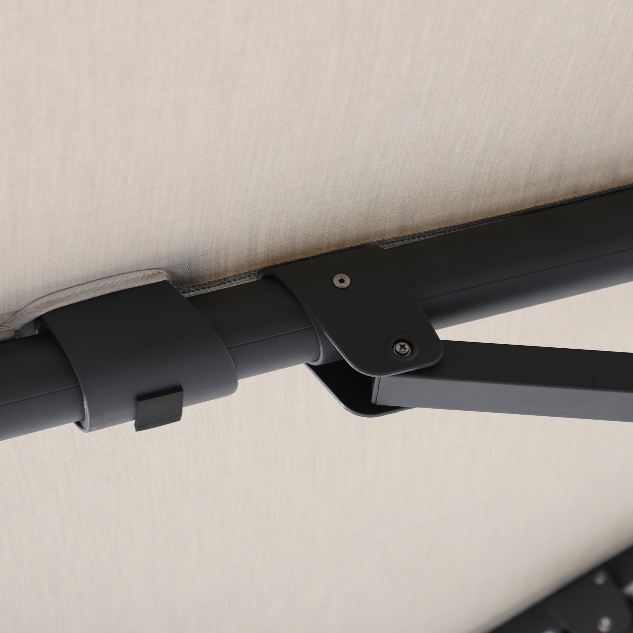 Close-up of a black metal hinge and bracket on a light panel, part of the Volos 3m x 4m Aluminium Cantilever Parasol with LED Lighting and 120kg Granite Base in Wheat.