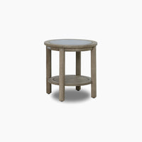 The Andora Round Side Table in Weathered Brown features a eucalyptus wood frame, glass top, and lower slatted shelf, displayed against a plain white background.