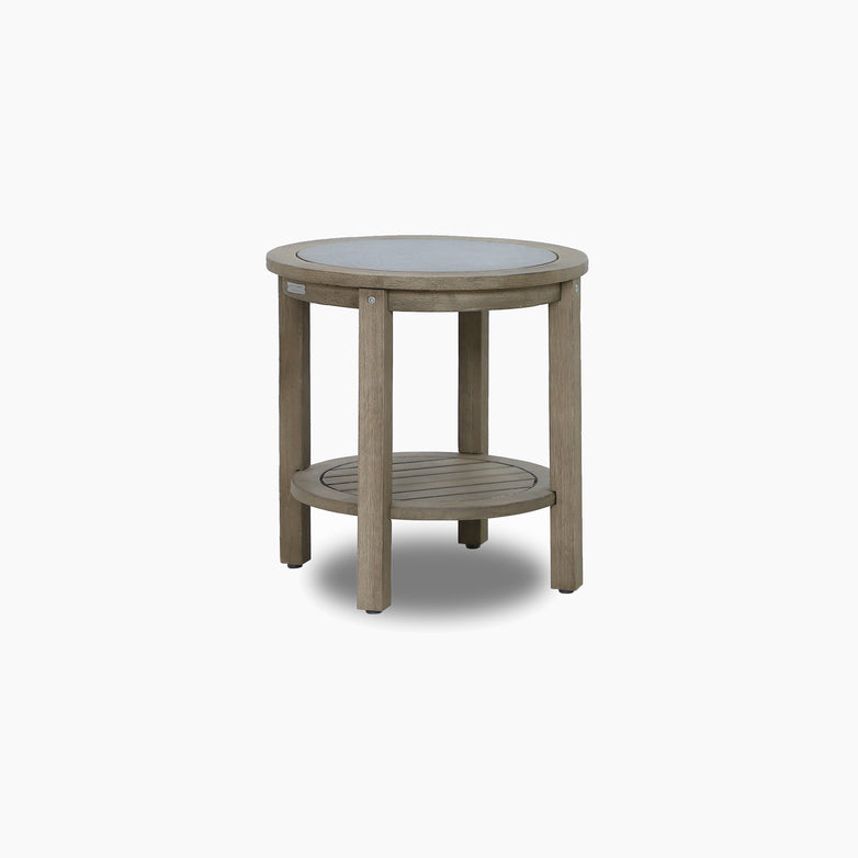 The Andora Round Side Table in Weathered Brown features a eucalyptus wood frame, glass top, and lower slatted shelf, displayed against a plain white background.