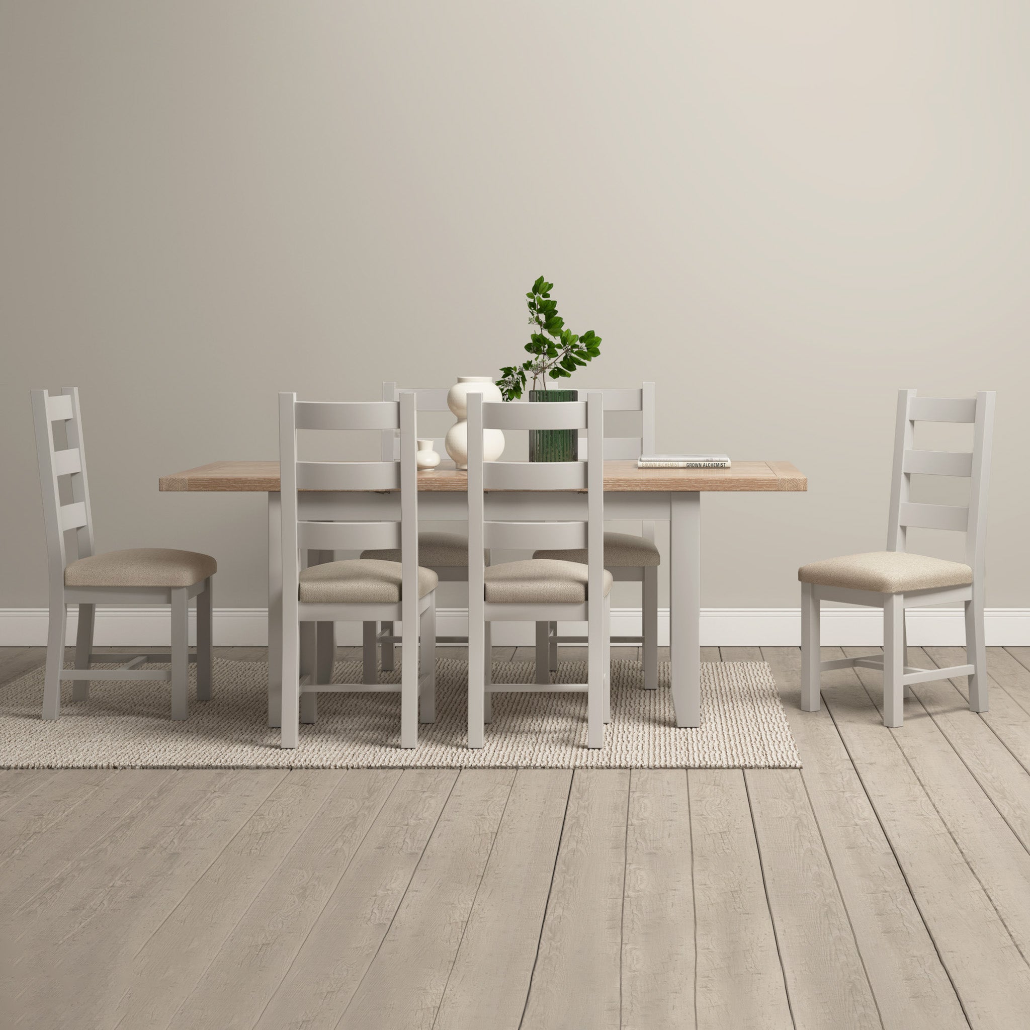 The Burford 6 Seat Extending Dining Set in Pebble Grey, paired with a plant centerpiece and neutral decor, creates a minimalist dining space.