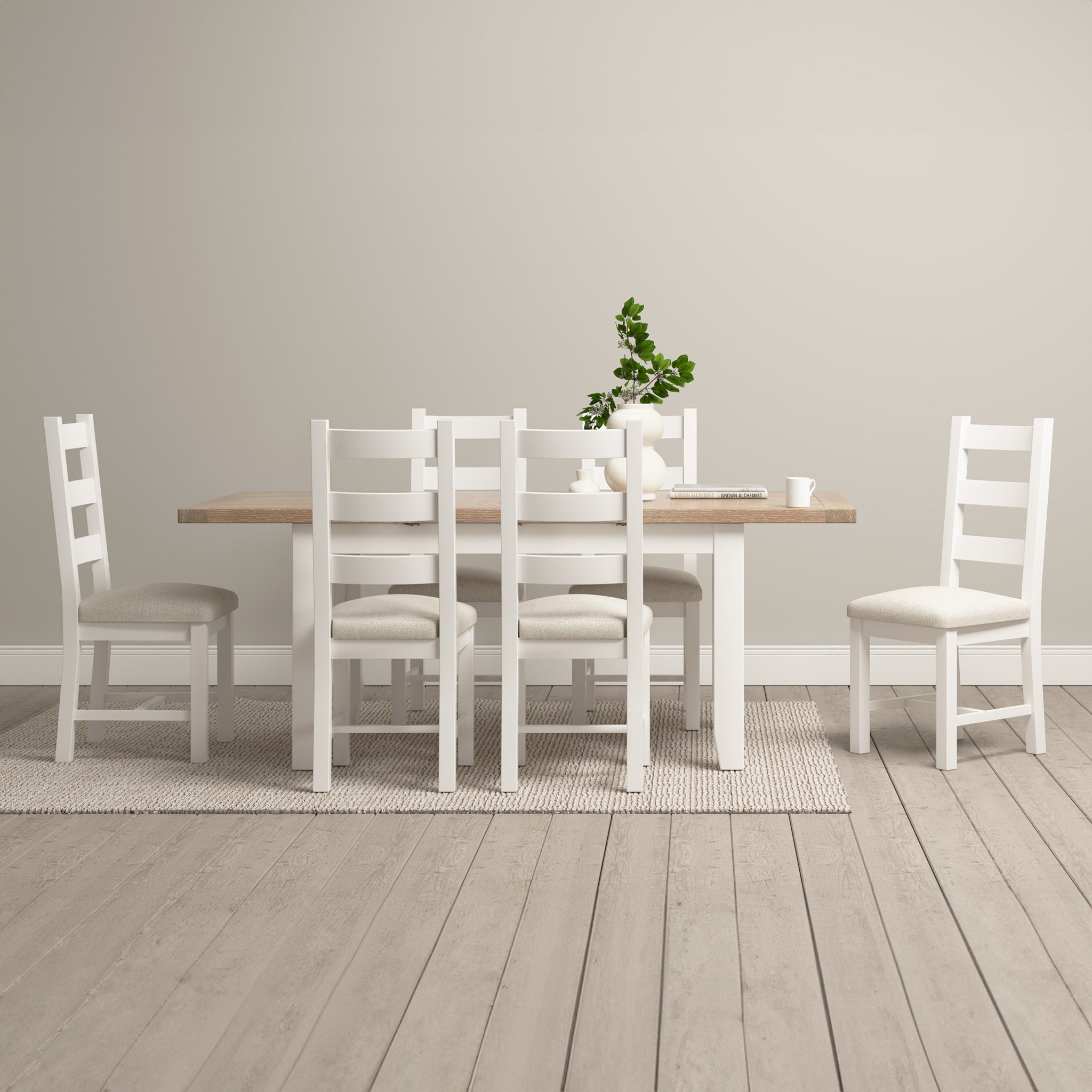 A minimalist dining room showcases the Burford 6 Seat Extending Dining Set in Warm White, featuring an extending wooden table and six matching chairs, complemented by a plant centerpiece on a light wood floor.