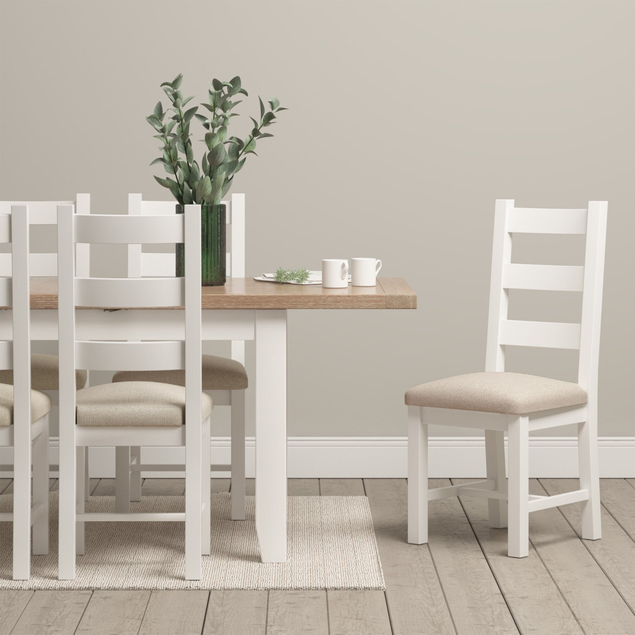 The Burford 8 Seat Extending Dining Set in Warm White stands out in the dining room. Natural oak craftsmanship is showcased by the extending dining table, which is surrounded by beige cushioned chairs and enhanced with a green plant centerpiece on the warm wooden floor.