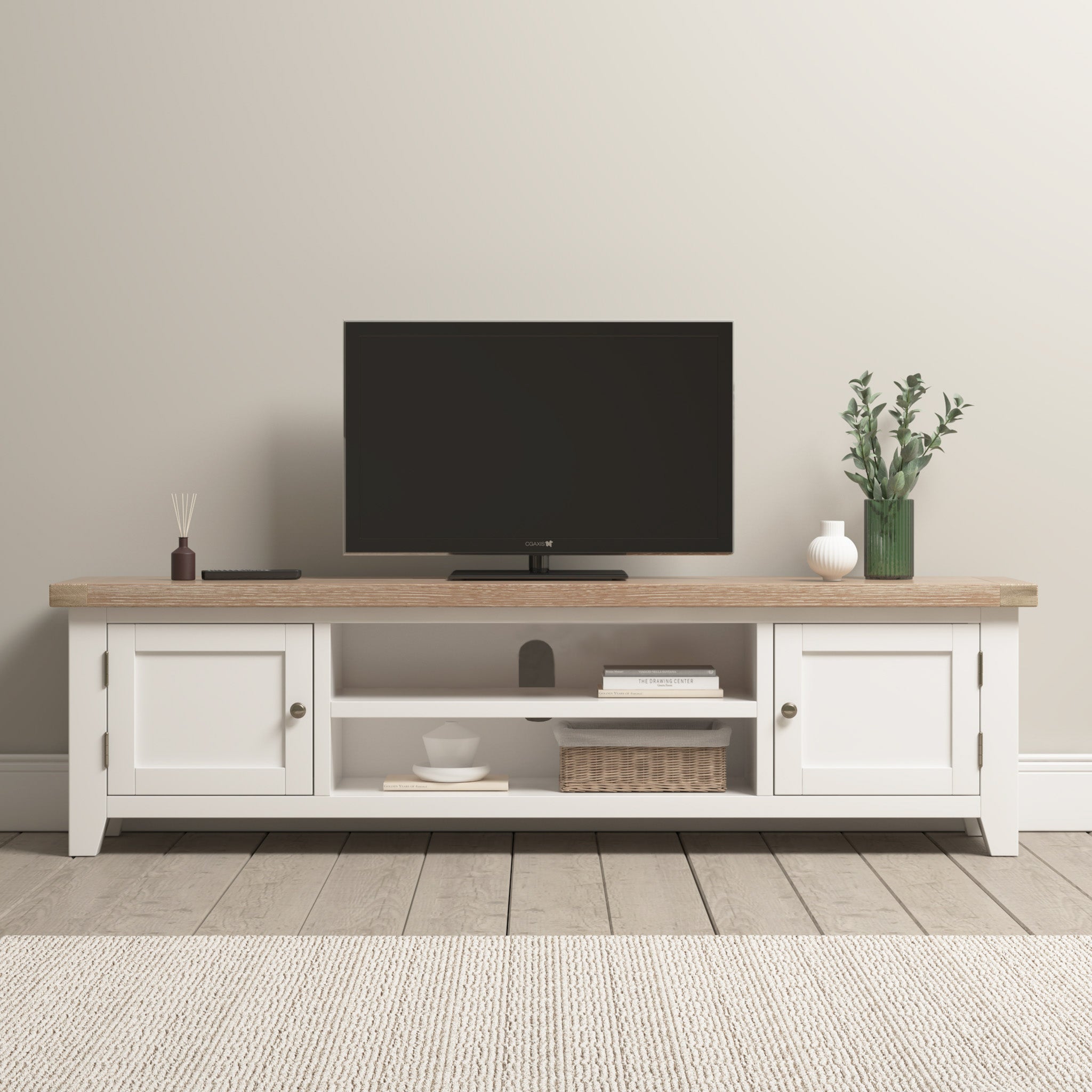 A TV sits on the Burford Large 180cm Media Unit in Warm White, adorned with decor items like a vase and basket in a bright, minimalist room. Nearby, the Burford Ladderback Dining Chair with a fabric seat and natural oak finish enhances the cozy yet stylish ambiance.