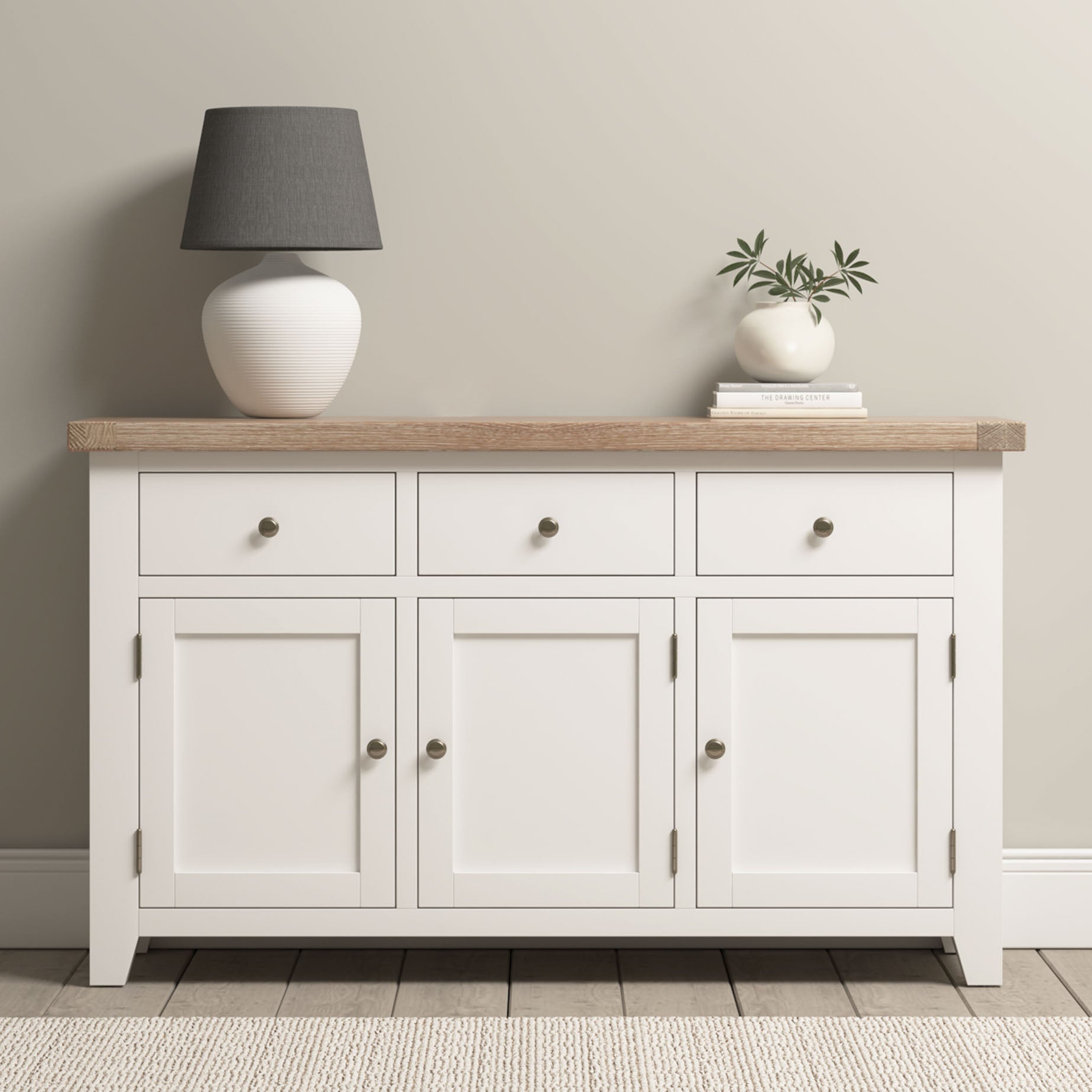 Burford Large 3 Door 3 Drawers Sideboard in Warm White with an oak top, styled with a gray lamp and a vase with greenery.