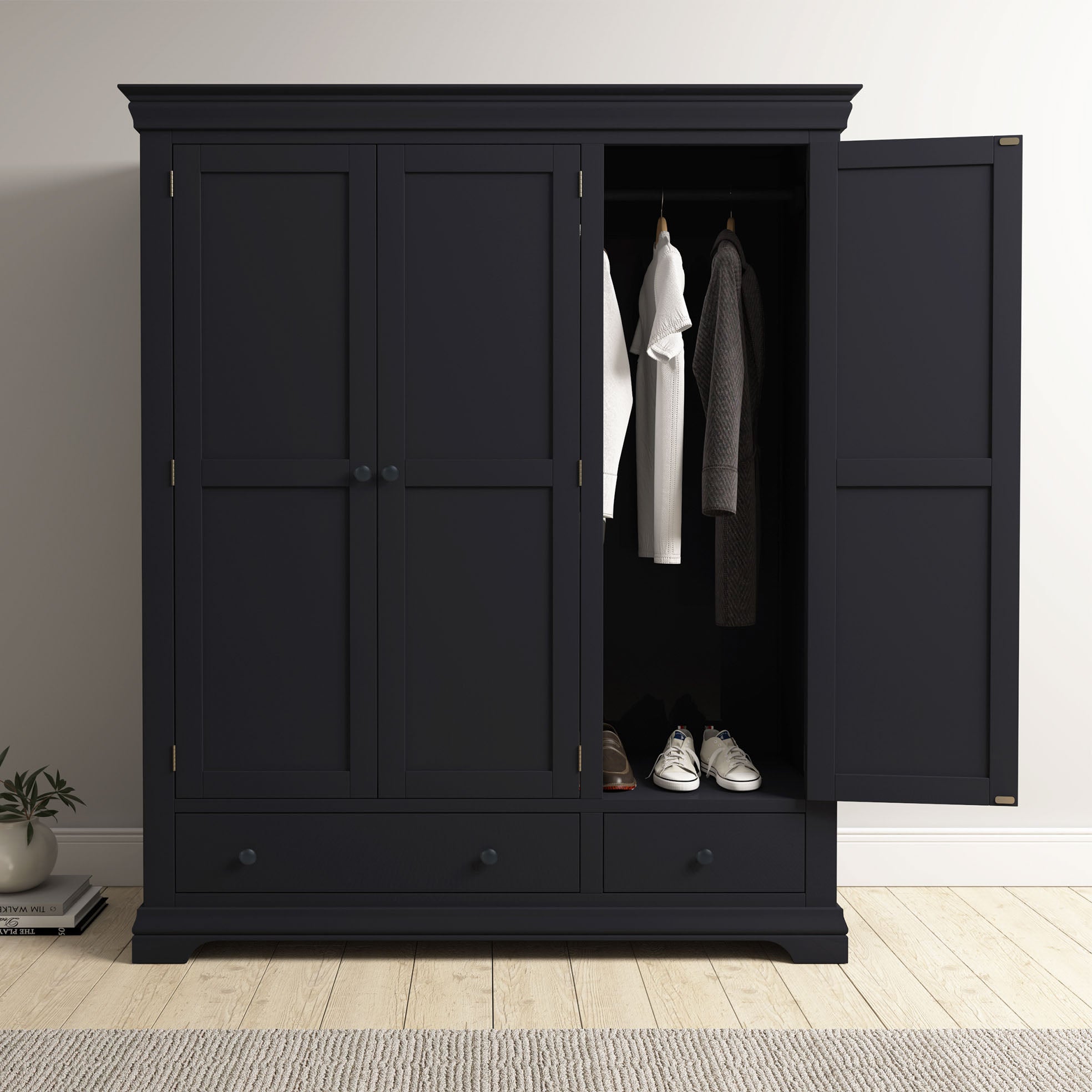 The Chalbury Triple Wardrobe in Dusky Black, with its open doors showing clothes and shoes inside, adds a sleek, modern touch to your bedroom décor.