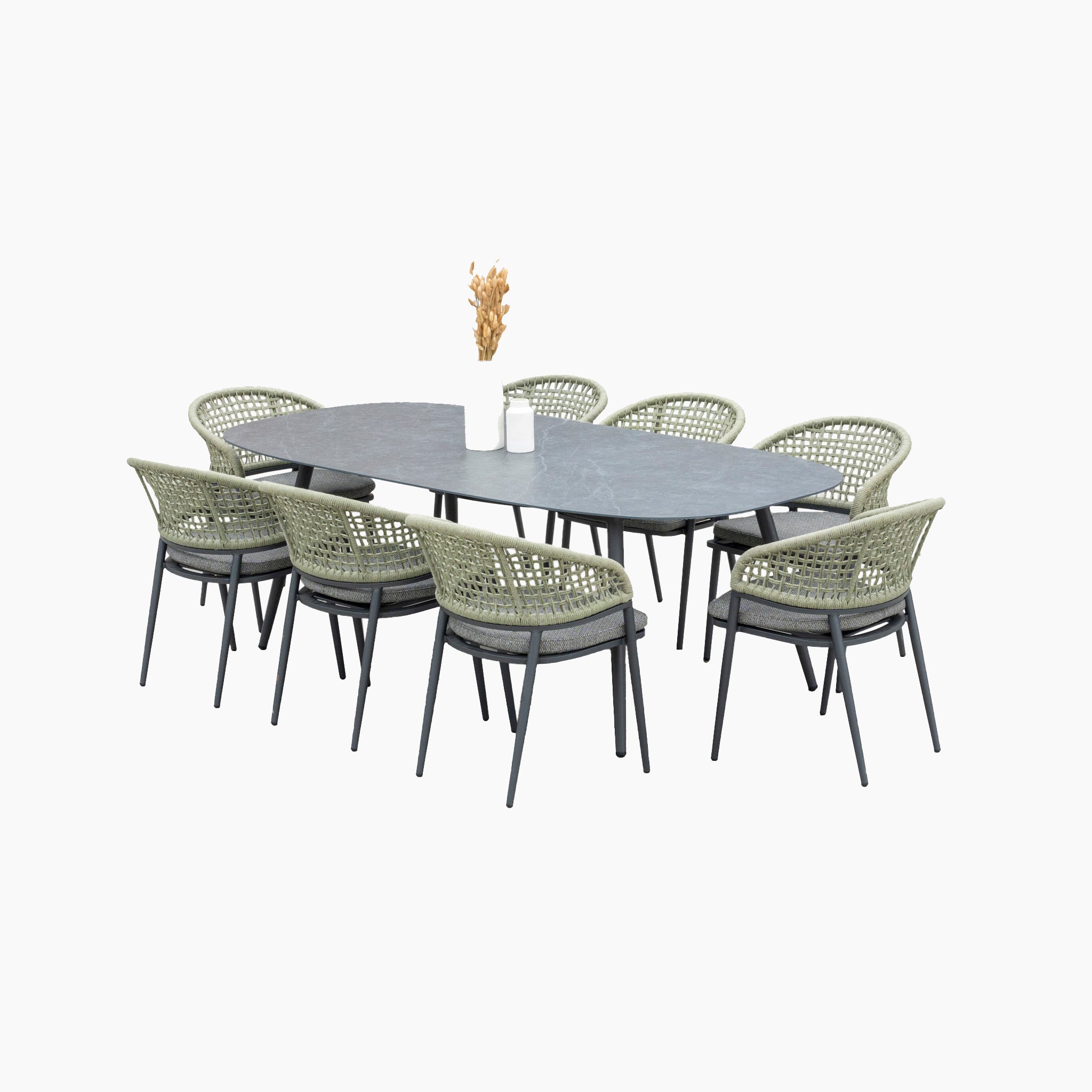 The Kalama 8 Seat Rope Oval Dining Set with Ceramic Table in Olive Green includes a dark table and eight olive green woven chairs made of weatherproof aluminum. A stylish white vase with dried flowers elegantly adorns the table, adding charm to any outdoor space.
