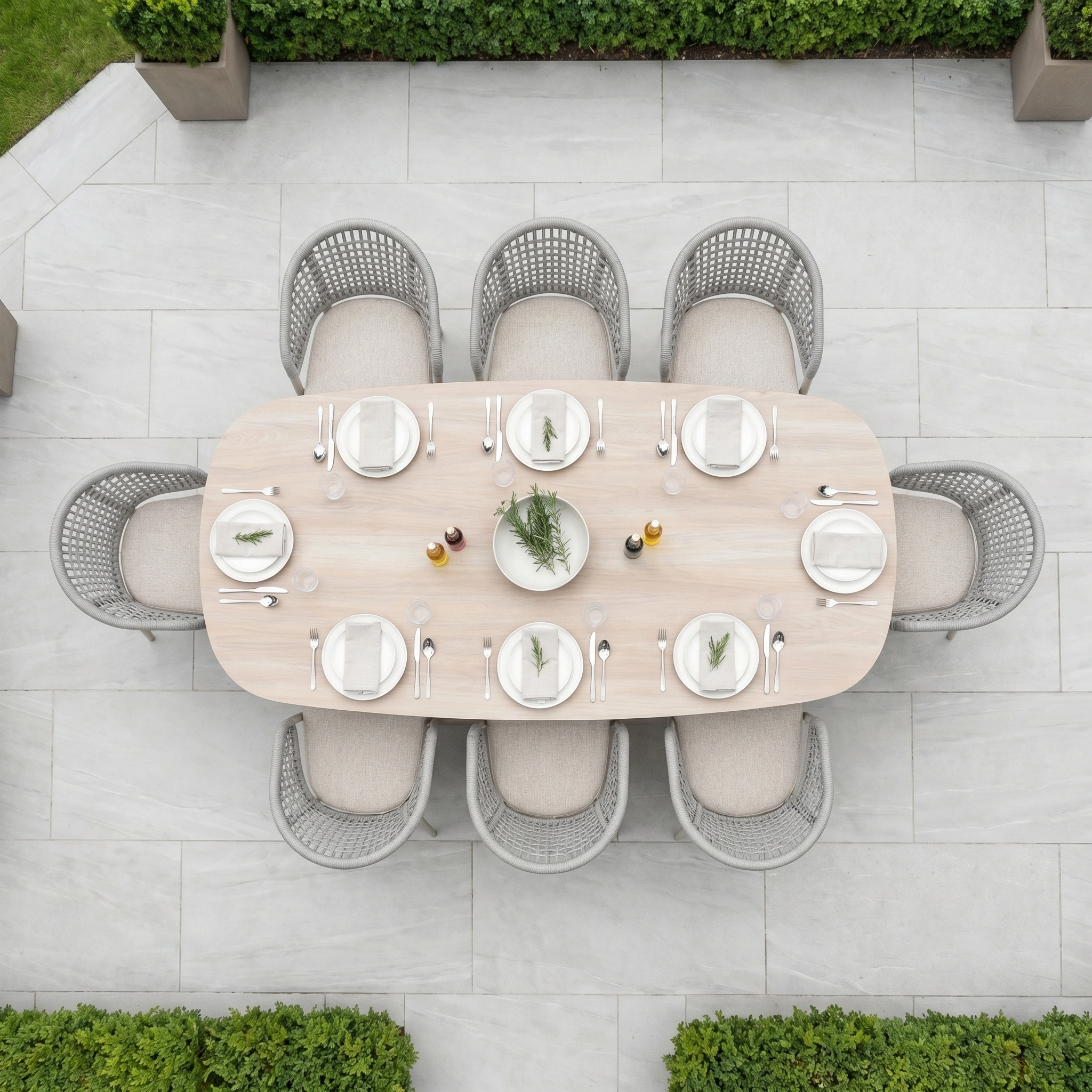 Weatherproof and stylish, the Kalama 8 Seat Oval Rope Dining Set in Oatmeal is arranged with plates, cutlery, and a greenery centerpiece—viewed from above—ideal for elegant outdoor dining.
