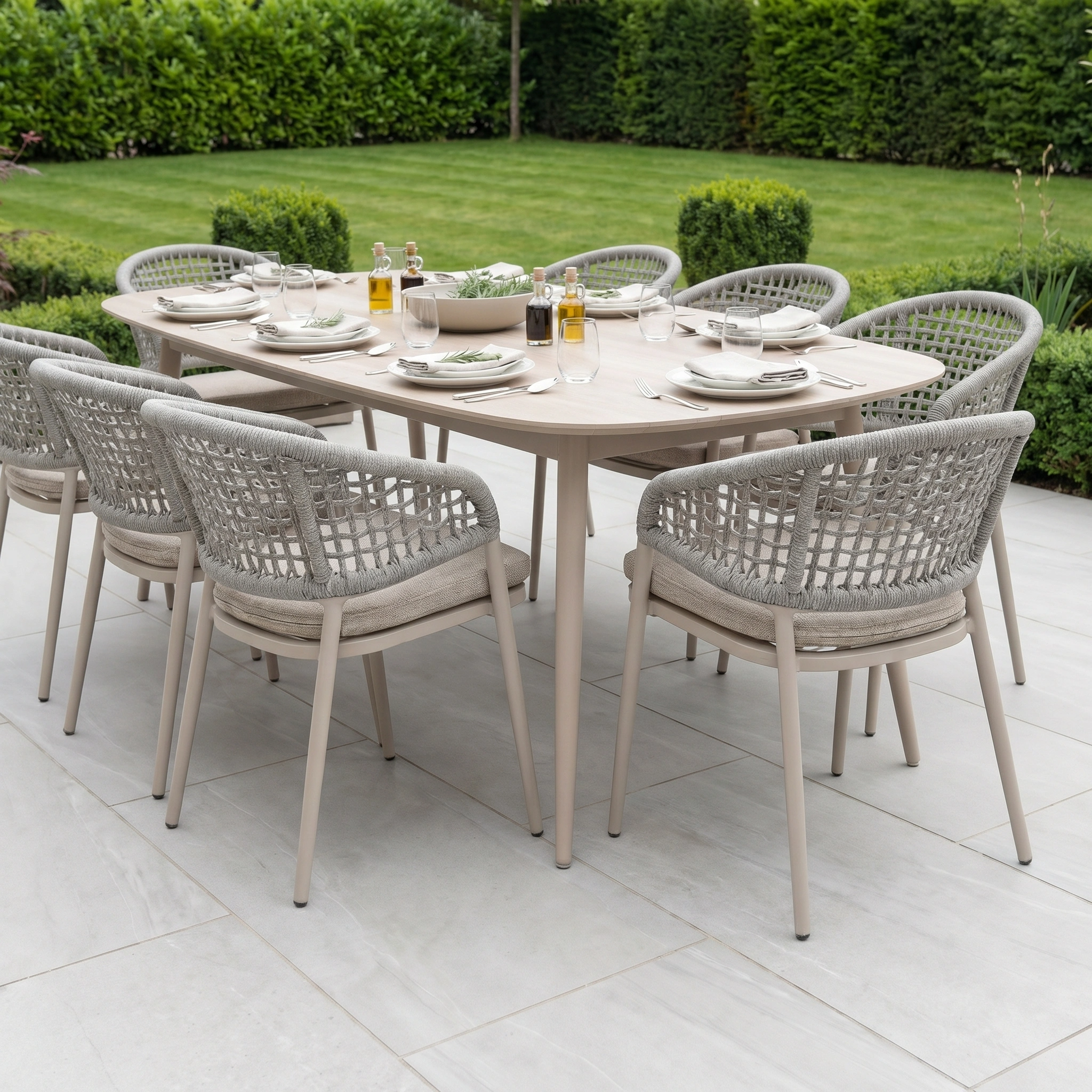 The Kalama 8 Seat Oval Rope Dining Set in Oatmeal features a stylish, weatherproof dining table and woven chairs—ideal for outdoor meals on your patio with a scenic garden backdrop.