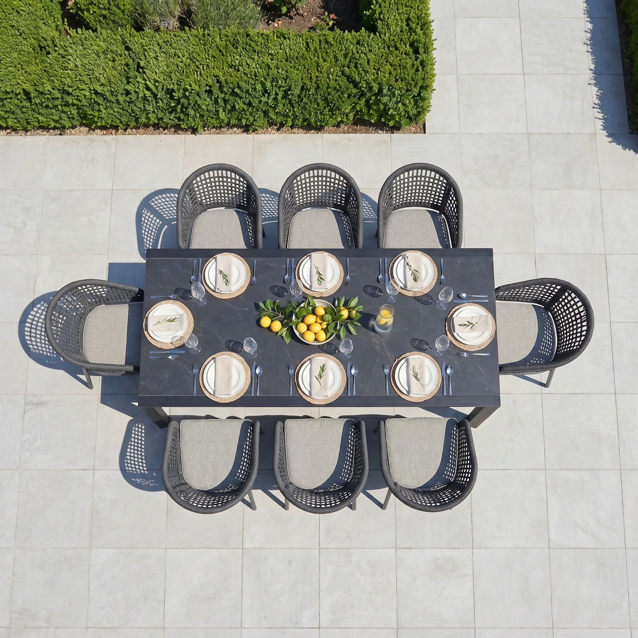 Aerial view of a modern Kalama 8 Seat Extending Dining Set with Ceramic Table in Truffle, an aluminium outdoor dining set elegantly decorated with lemons and greenery.